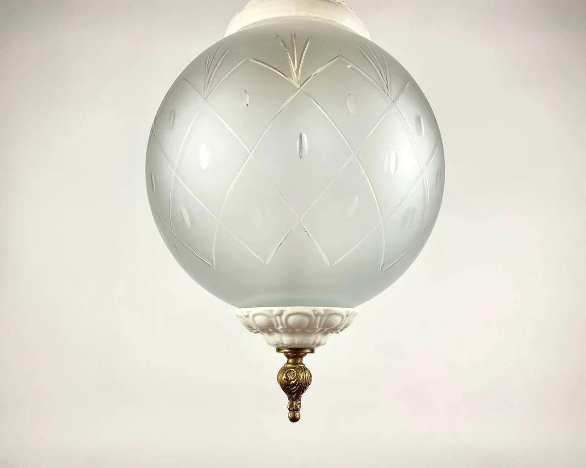 Magnifique lustre à pendentifs de style français. Cadre en porcelaine blanche, décoré de jolies fleurs en relief et d'un abat-jour sphérique en verre dépoli. Les parties métalliques sont en bronze. Le minimalisme et une combinaison harmonieuse de