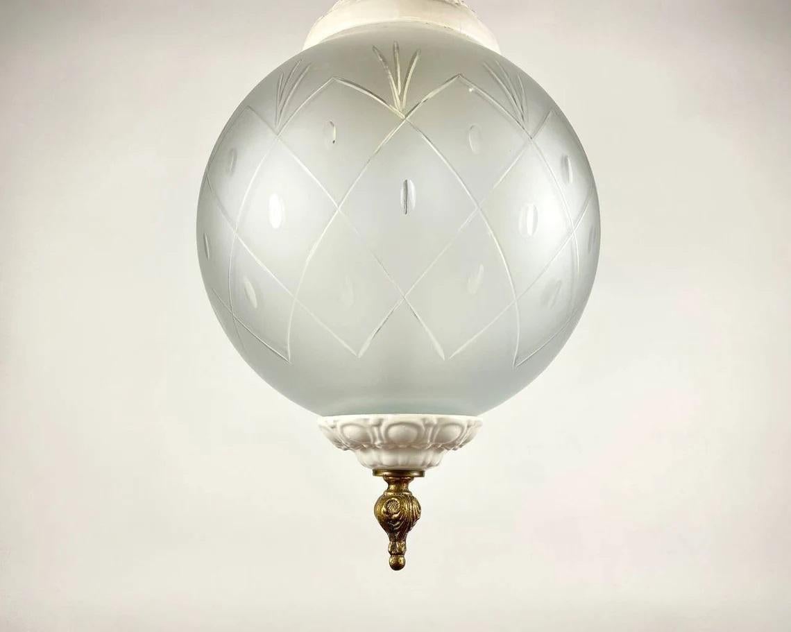 Beautiful Vintage French Pendant Chandelier. White Porcelain frame, decorated with cute relief flowers and a spherical shade of frosted glass. Metal parts are made of bronze. Minimalism and a harmonious combination of details do not load the space.