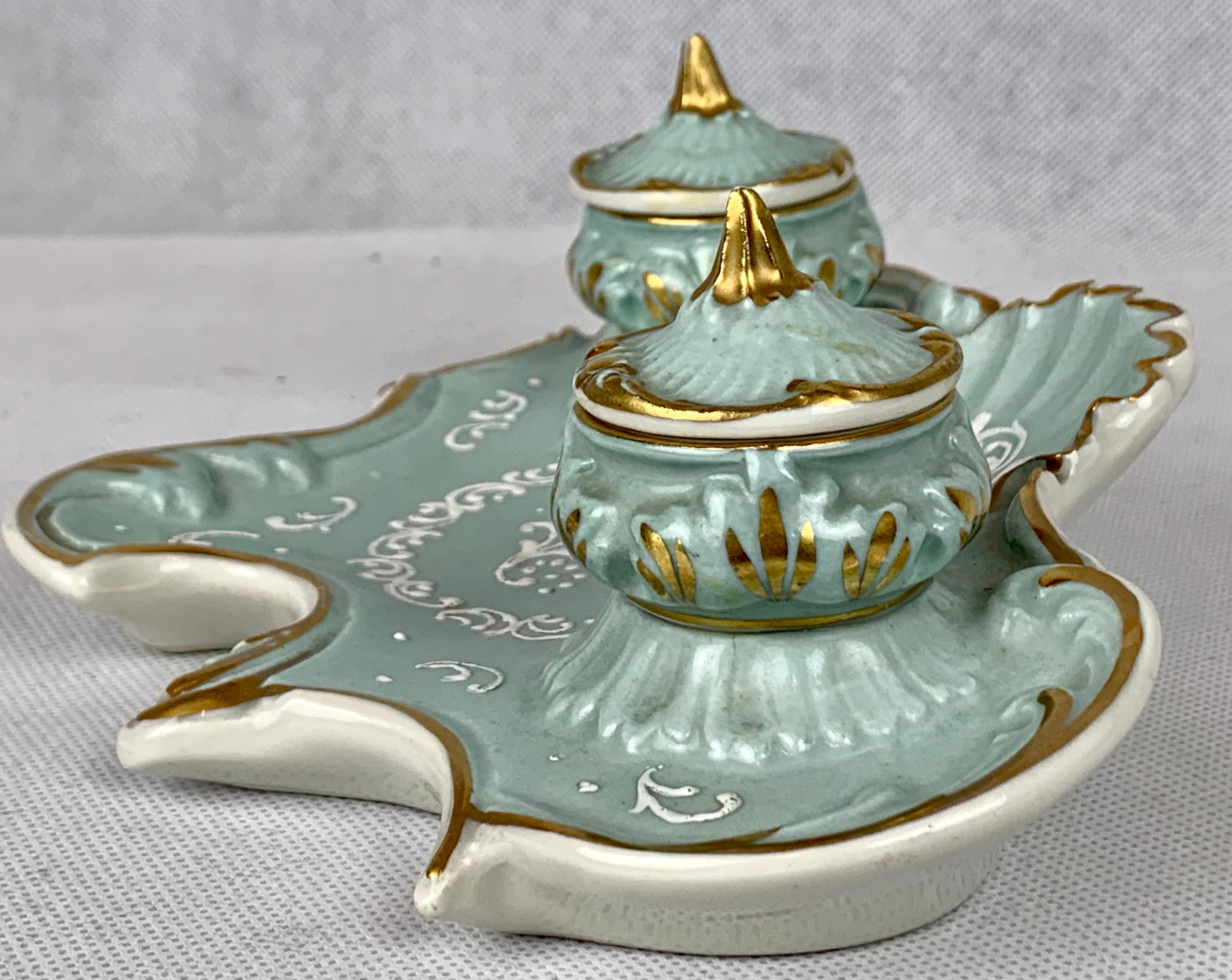 French porcelain inkstand with double inkpots in a soft sea foam color. The decoration is in white Pate-sur-Pate enamels. The inkpot covers are removable. The covers and the inkstand are trimmed in a soft gilt finish. You will find the bottom of the