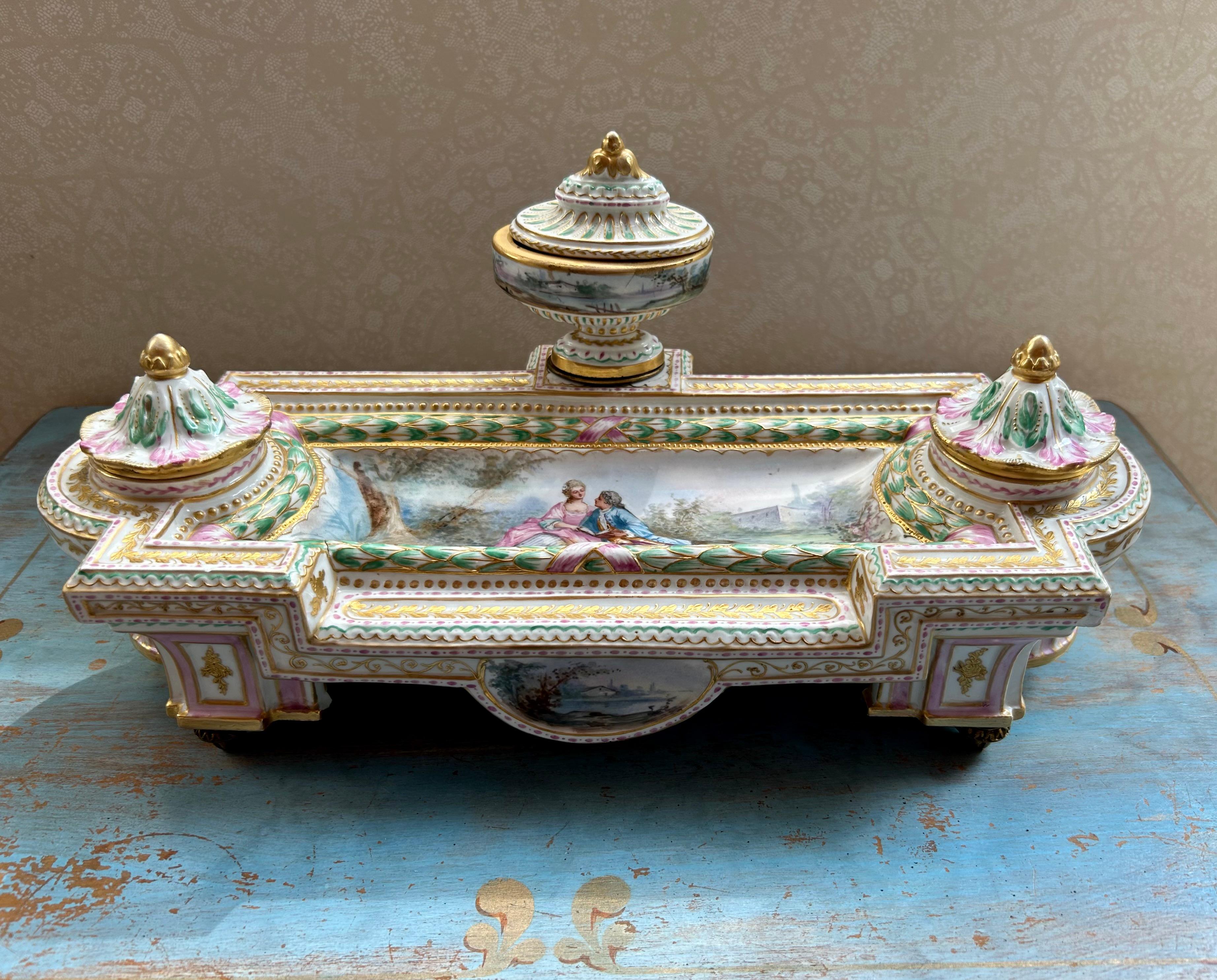 Dies ist ein exquisites vergoldetes und emailliertes Porzellan-Tintenfass im Sèvres-Stil aus Frankreich. Neunzehntes Jahrhundert.
Das Tintenfass besteht aus einer länglichen Schale mit zwei abgedeckten Tintenfässern, die eine zentrale Vertiefung