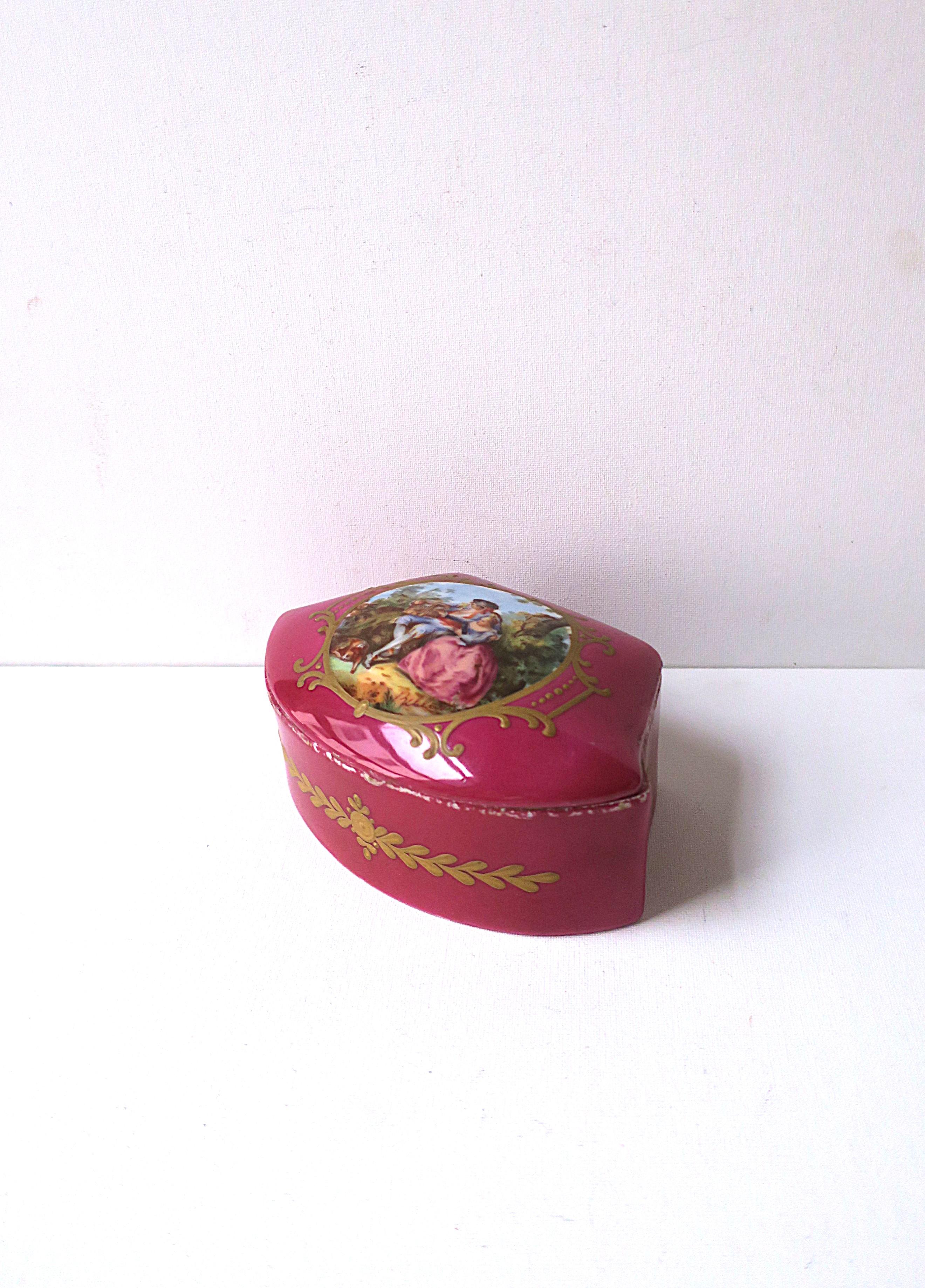 A French porcelain jewelry box, styled after Sèvres porcelain, in the Regency design style, circa late-19th century to early-20th century, France. Boxes' lid features outdoor nature scene with couple and dog surrounded by hand-painted gold detail i