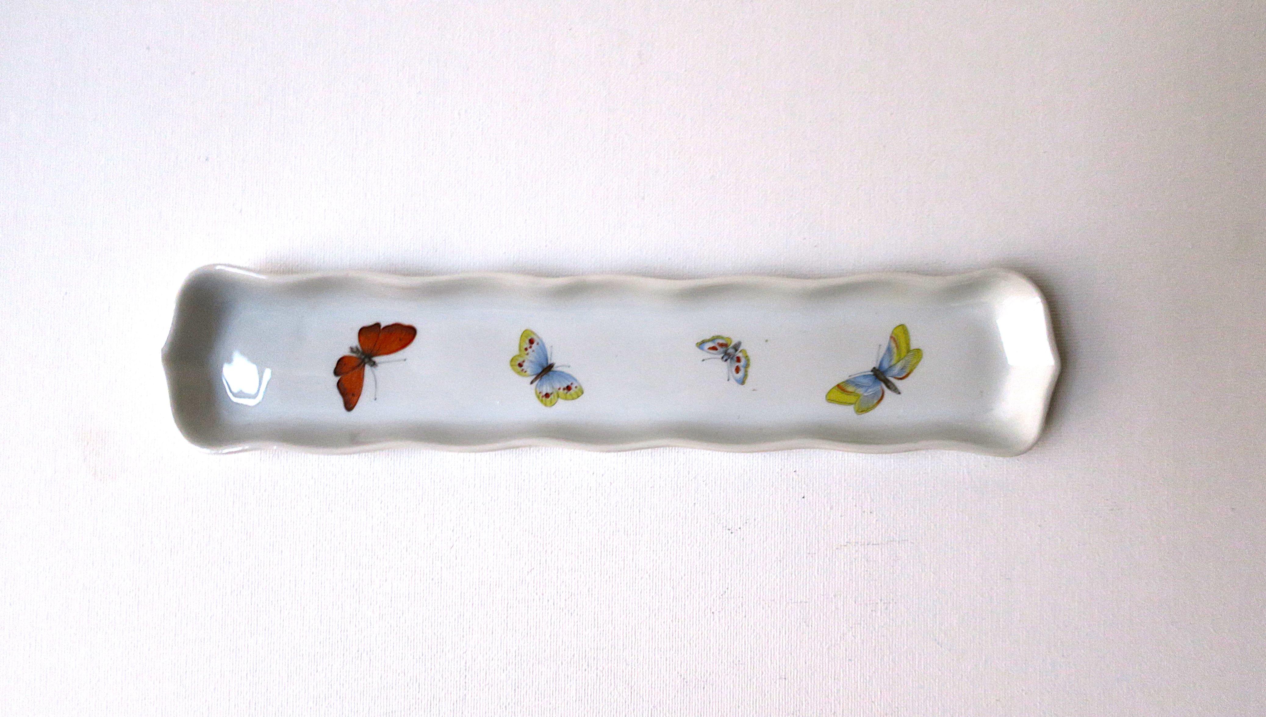 A French porcelain jewelry dish with butterfly design, circa mid-20th century, France. Made in France. A beautiful oblong piece with decorative edge and colorful butterflies. Great for holding jewelry on a dresser, nightstand table, vanity, desk,