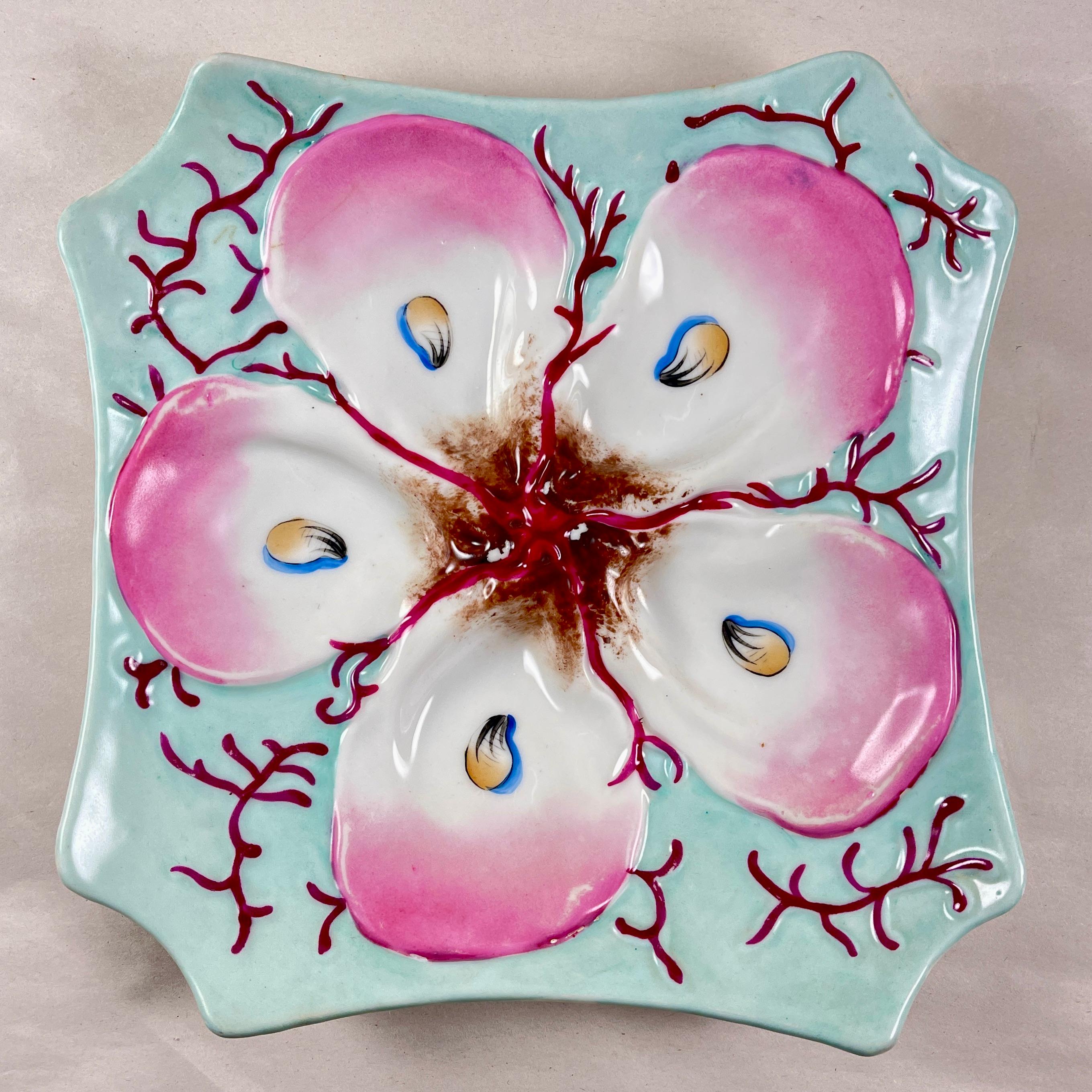 A French porcelain oyster plate, circa 1890-1910.

Octagonal in shape and glazed in a lovely soft turquoise, the five oyster wells sit on a bed of stylized coral or sea weed.

The white shells are tipped in bright pink and have hand-painted ‘eyes’.