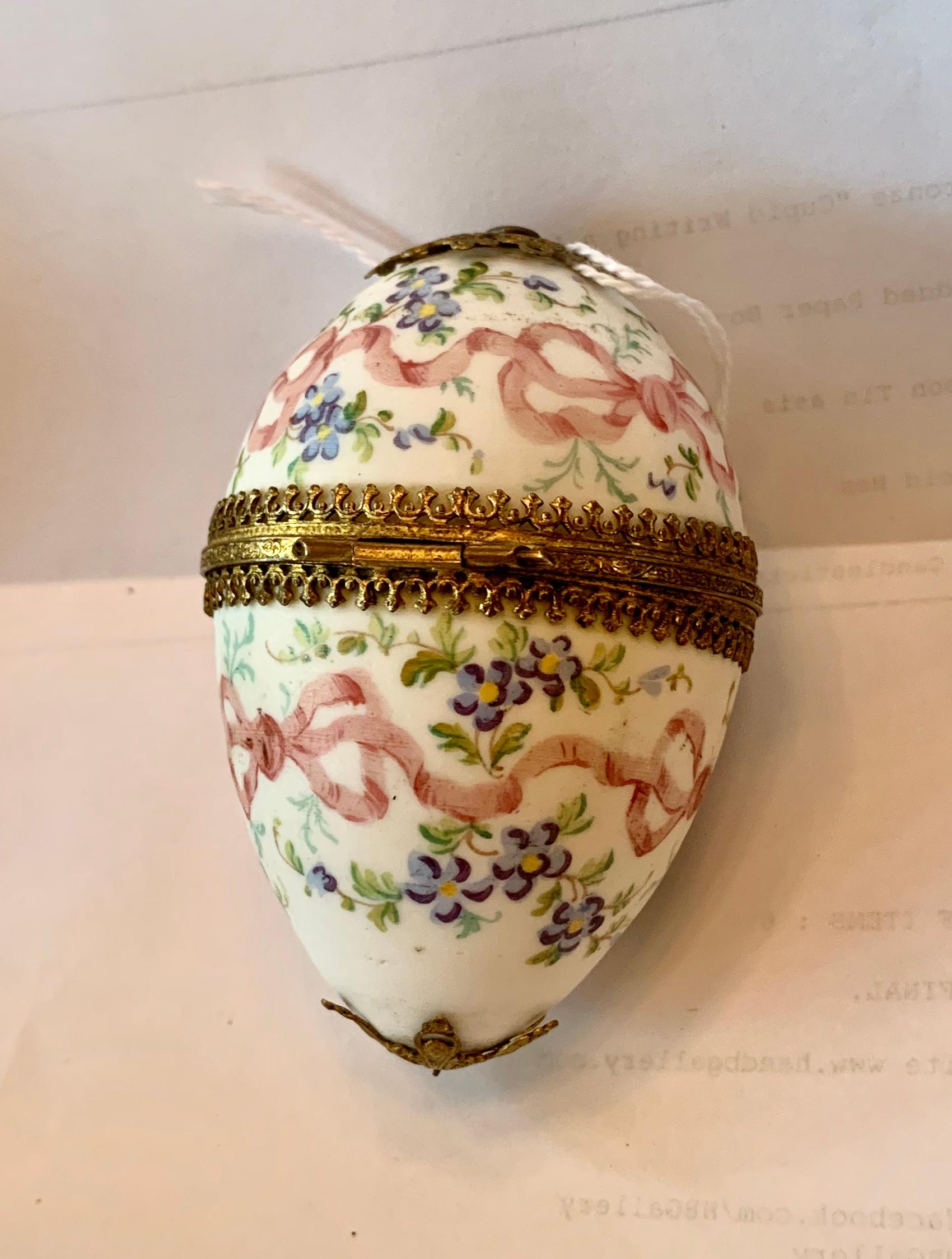 This is a stunning antique French Belle Epoque - Victorian egg box in porcelain with gilt ormolu mounting and hand painted decoration of pink ribbons and bows with Forget-me-not flowers.  The delicate romantic egg box is exquisite.  The hand painted