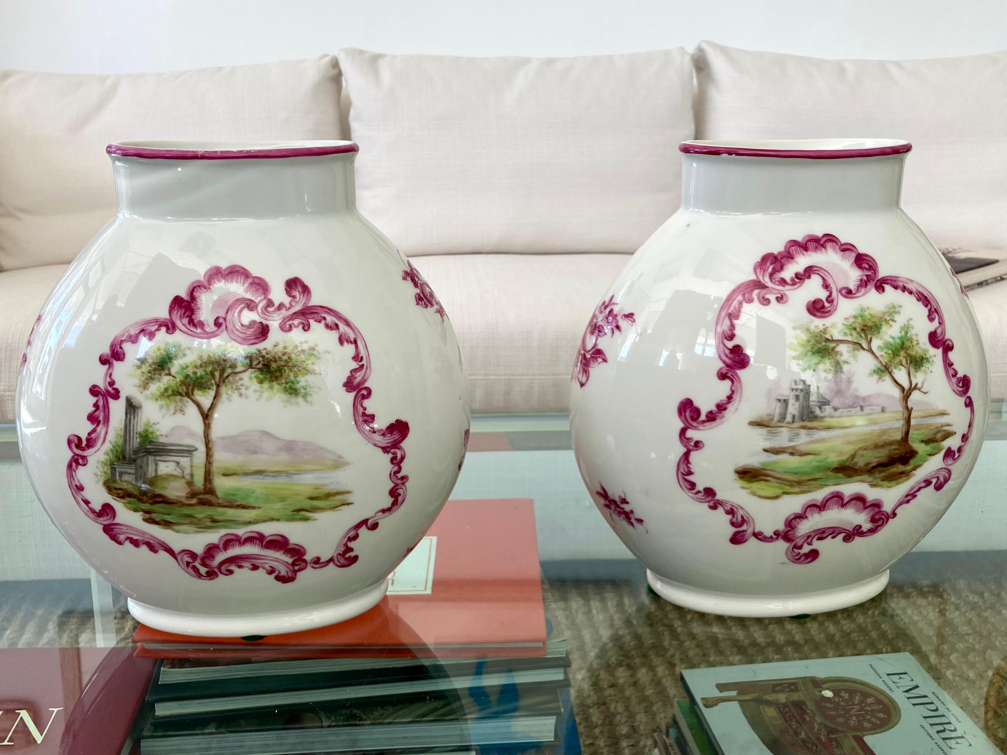 French 19th Century pair of porcelain oval vases with decorative hand painted landscape scenes. Beautiful pink hand painted details and a true pair!