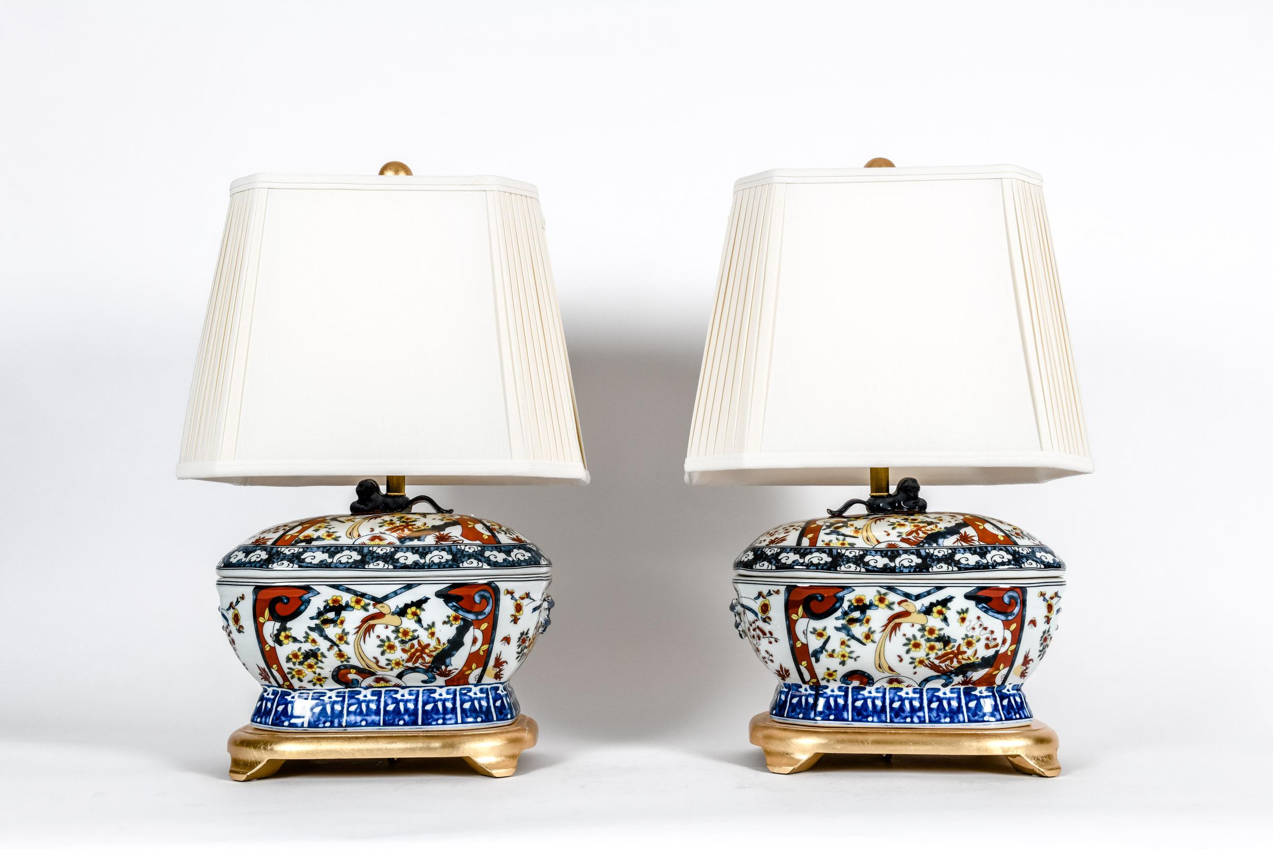 French porcelain, pair late 20th century table lamps with footed giltwood base. Each lamp is in excellent working condition, minor wear consistent with use or age. Measures: Each comes with a pleated silk shade size 11 inches tall x 11.5 inches top