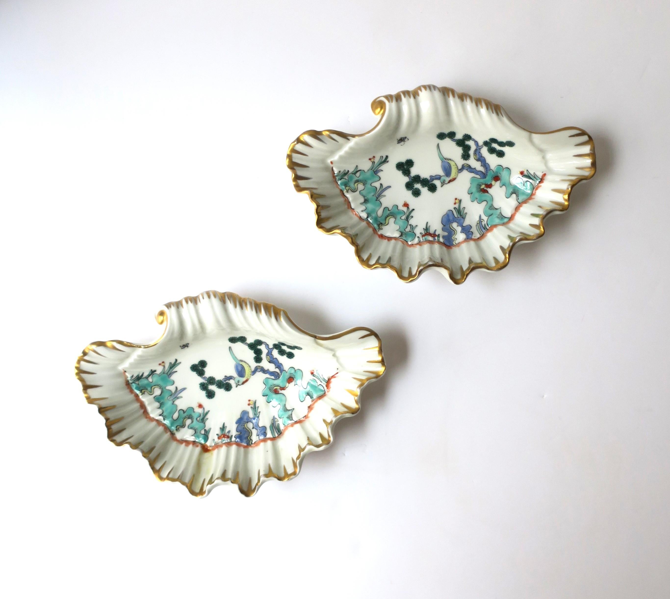A beautiful pair of French porcelain seashell bowls with bird design, circa early-20th century, Paris, France. These porcelain seashell bowls have a colorful raised relief of a bird and tree design with surrounded by gold detail. These seashell