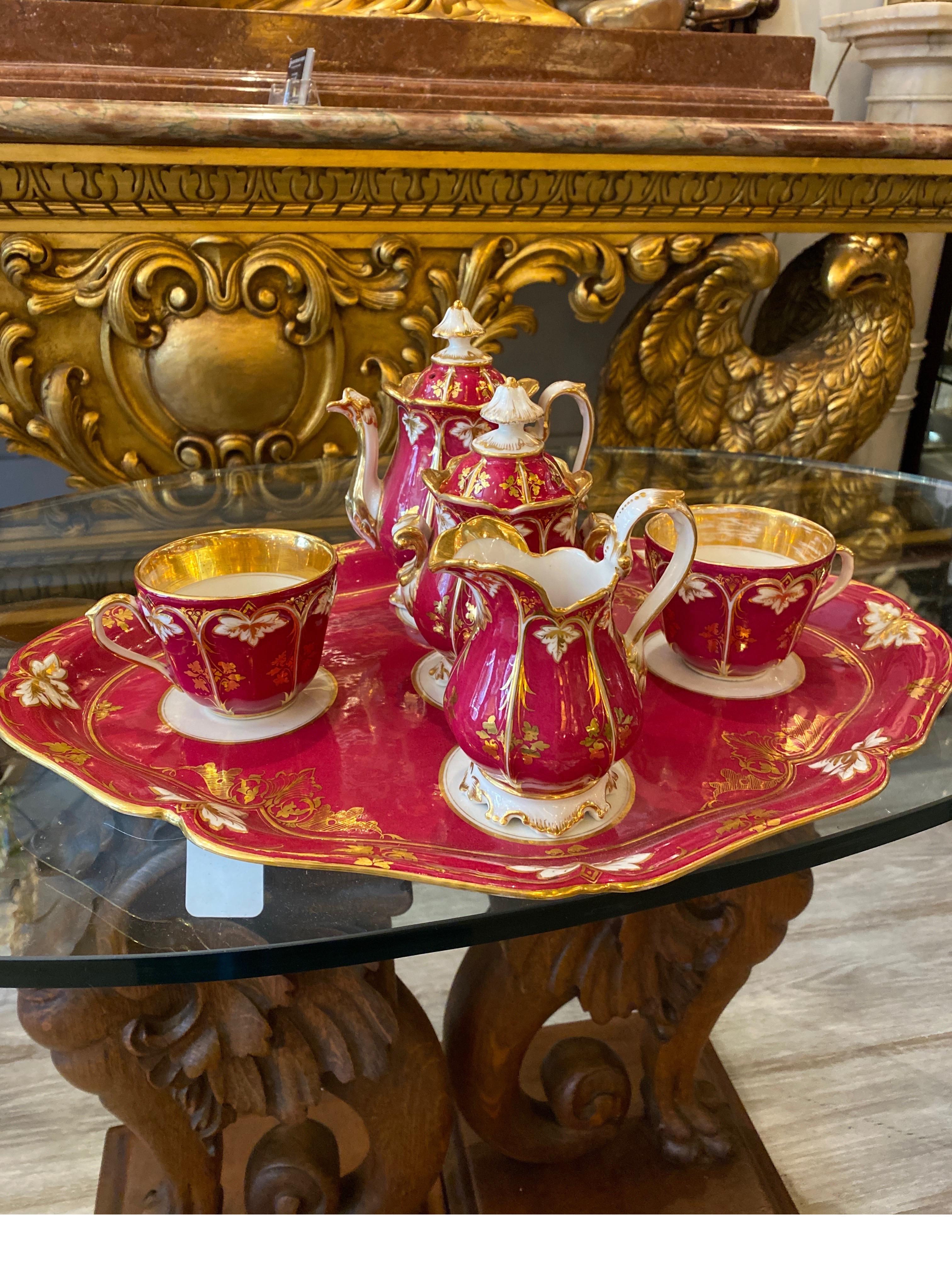 Elegant 19th century porcelain in white gold and crimson raspberry. The teapot with lid, sugar bowl with lid, creamer, two tea cups with tray. The tray measures 17 wide, 12.75 deep and the small tea pot is just 7 inches tall.