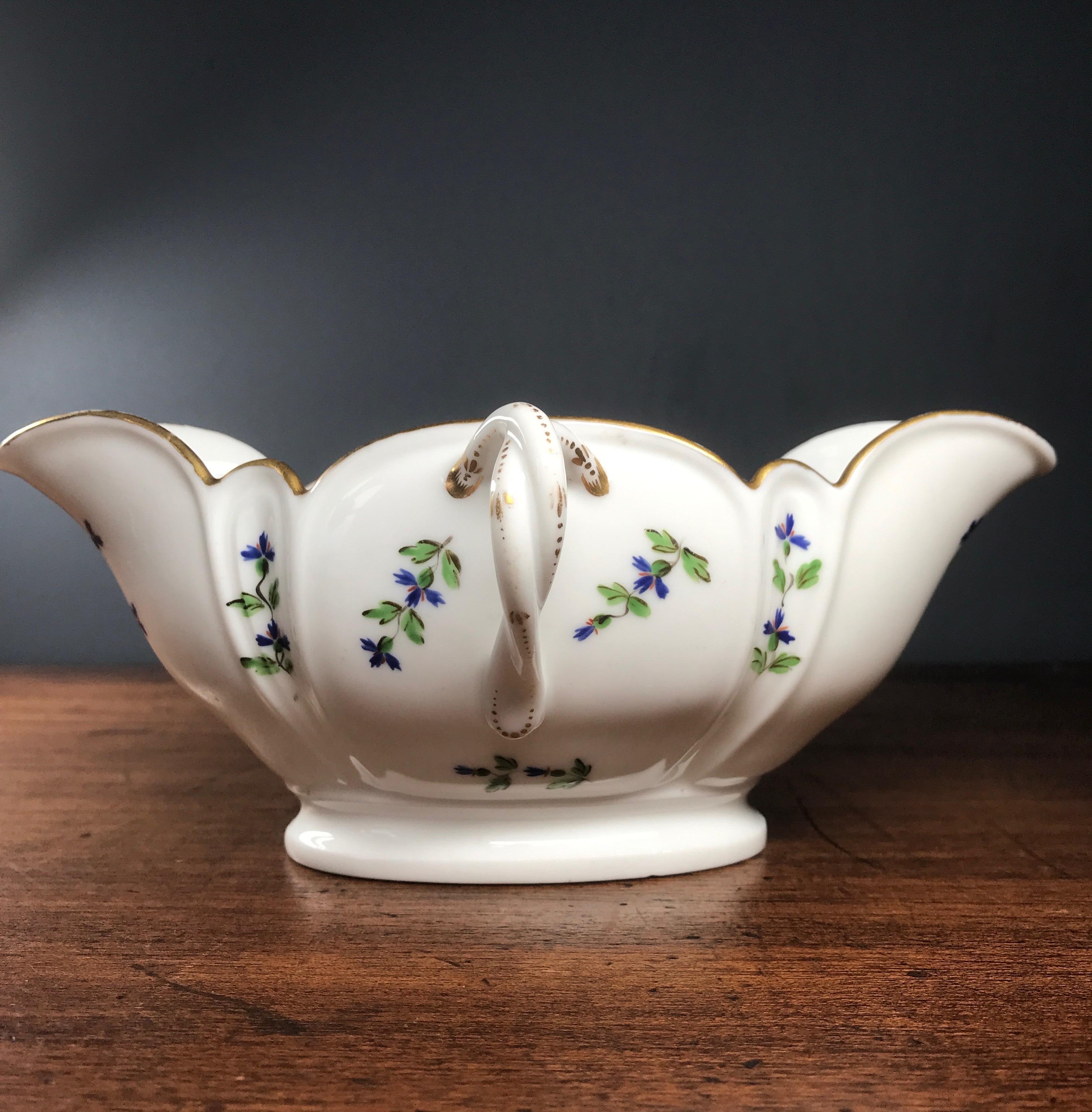French porcelain sauce boat of lobed couple spouted form, the twin handles of double twist design, the whole decorated with green, blue and red cornflowers, within a gold line rim. 
Partial mark, CP beneath a crown, Paris, 
probably Comte