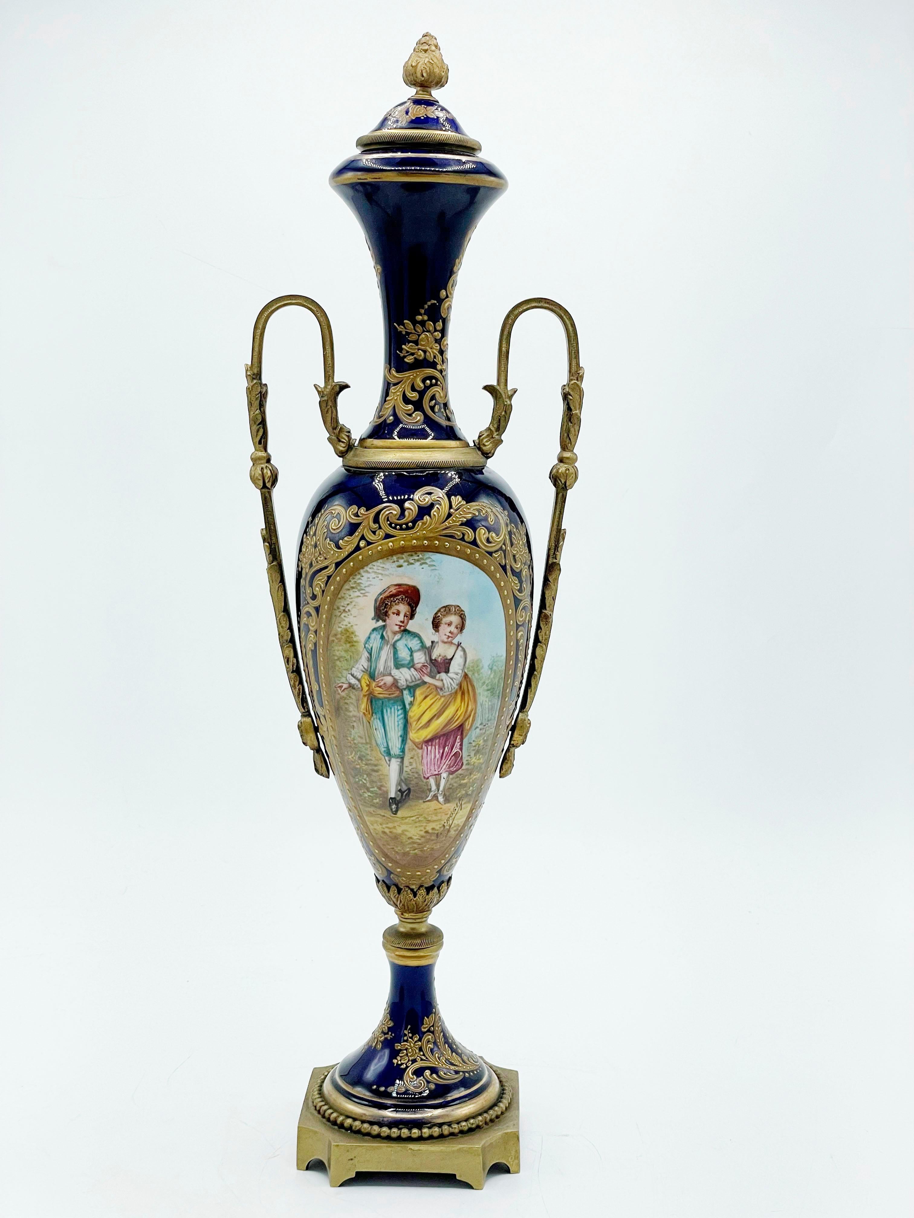 French porcelain vase, Sevres, with Cloisonne bronze
French porcelain vase with gilt base, with gilt bronze handles with a painted landscape on one side and a couple of children inside gilt cartouches, signed 