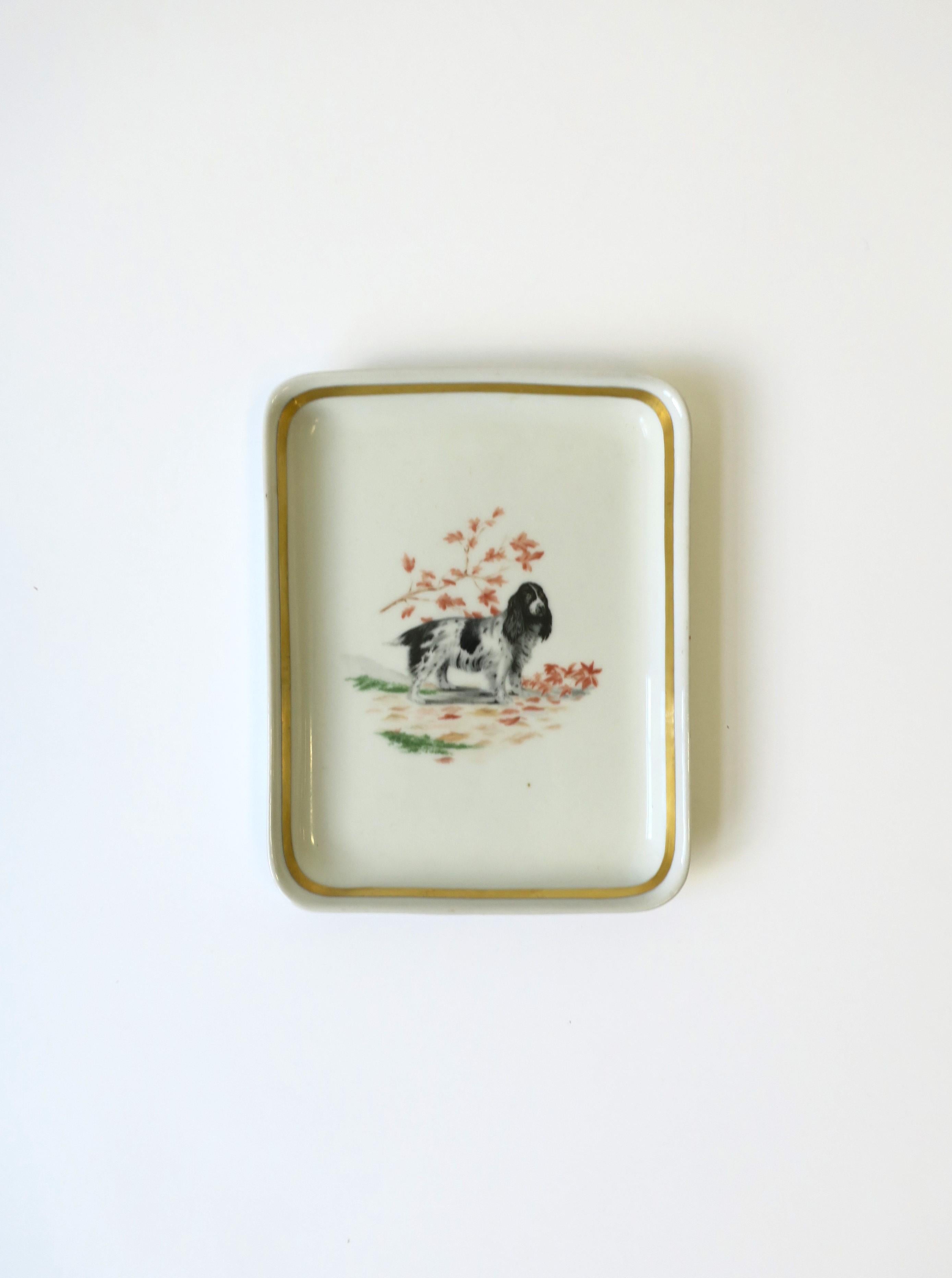 A beautiful French porcelain vide-poche catchall jewelry dish with black and white spaniel dog, circa mid-20th century, France. This porcelain tray/dish is rectangular, with gold band around interior, black and white spaniel dog at center, and a