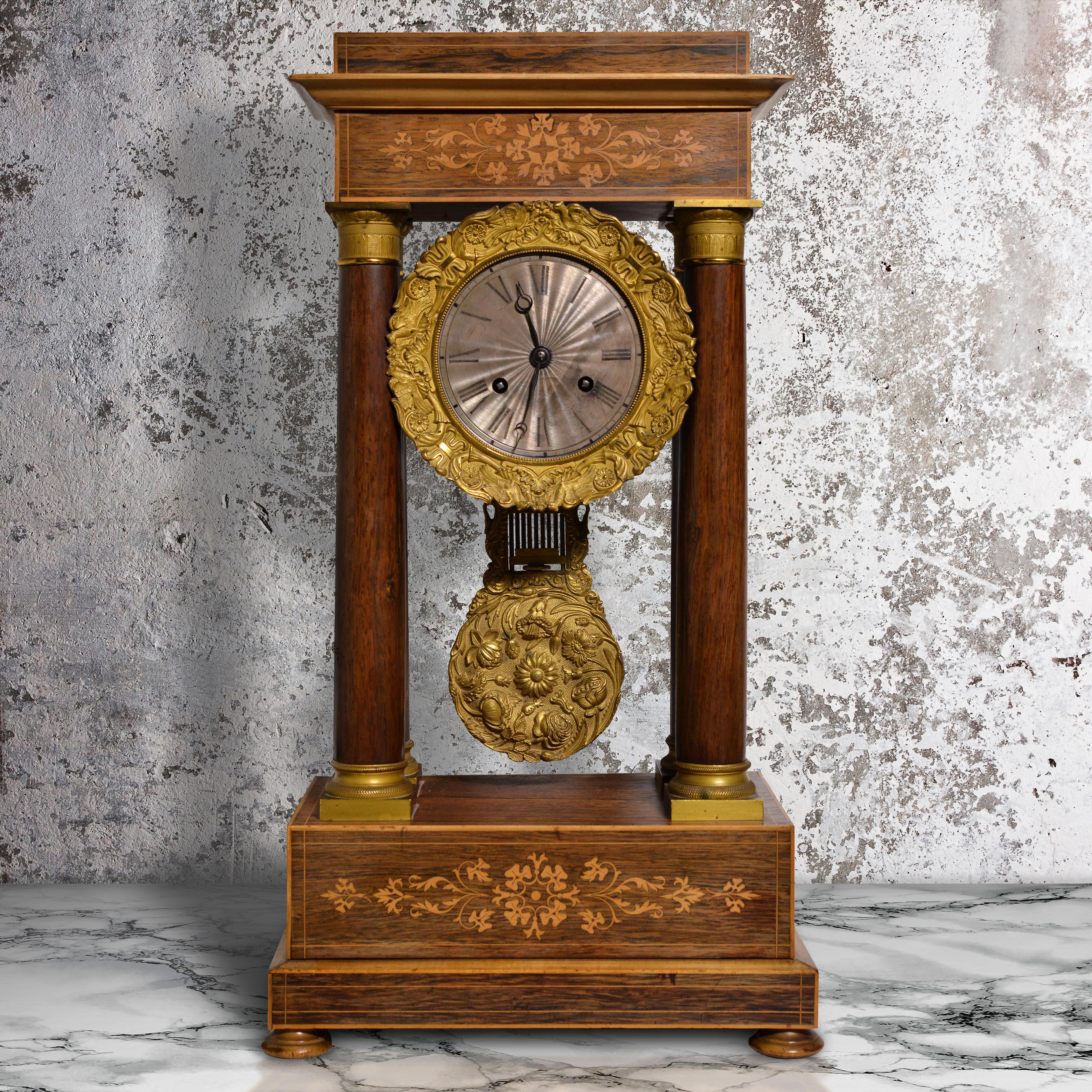 Orologio da camino (mensola, scrivania) Portico intarsiato in legno di palissandro e mogano di epoca Charles X. L'orologio ha una sommità a frontone su un architrave intarsiato. Quadrante centrale in argento rabescato con numeri romani alla