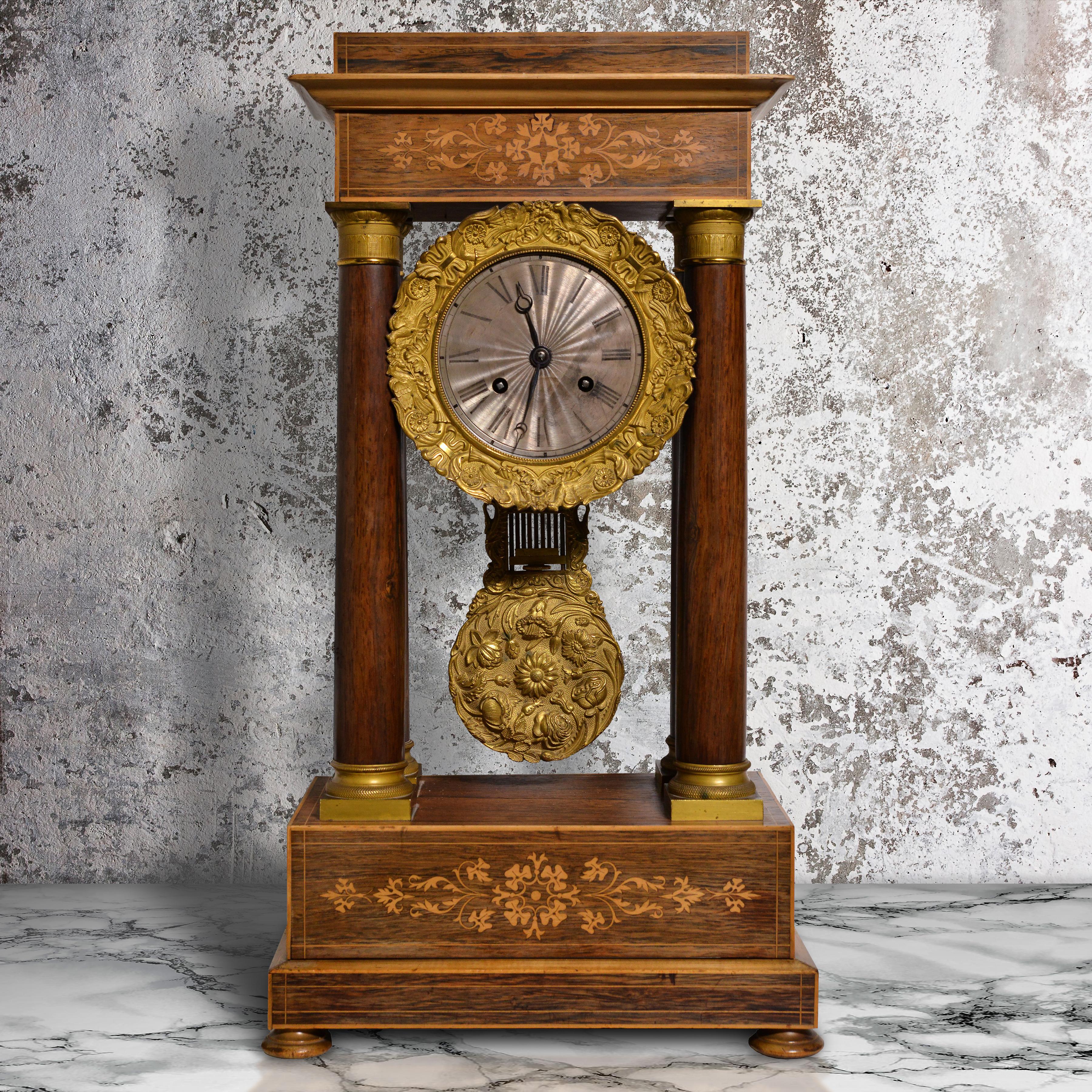 Pendule de cheminée (étagère, bureau) Portique en marqueterie de bois de rose et d'acajou d'époque Charles X. L'horloge est surmontée d'un fronton et d'une architrave incrustée. Cadran central en argent guilloché avec chiffres romains à l'anneau de