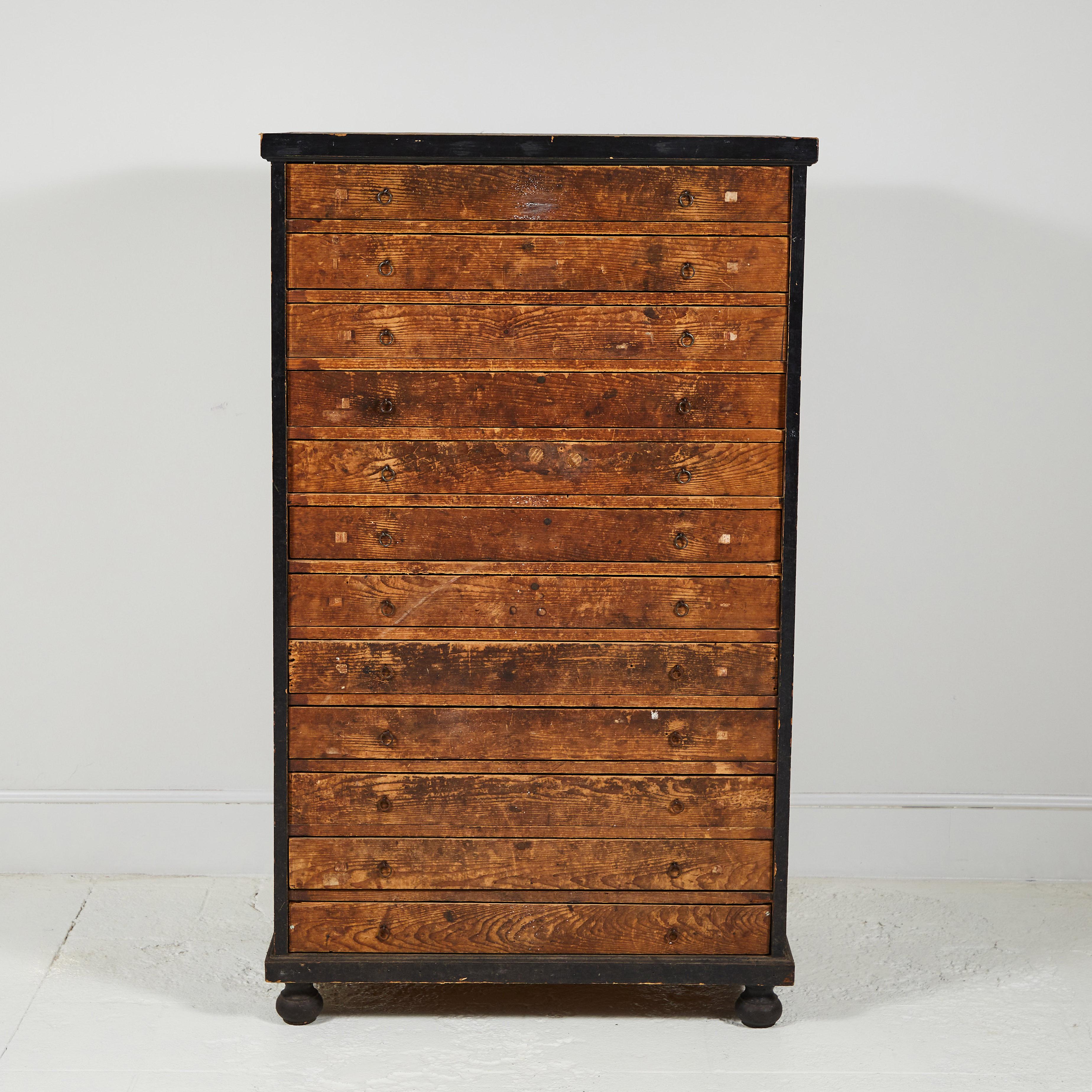 French Primitive tall chest of drawers, the body consists of a black painted frame with rustic wooden drawers. Each drawer is shallow and is the same size.
 
 