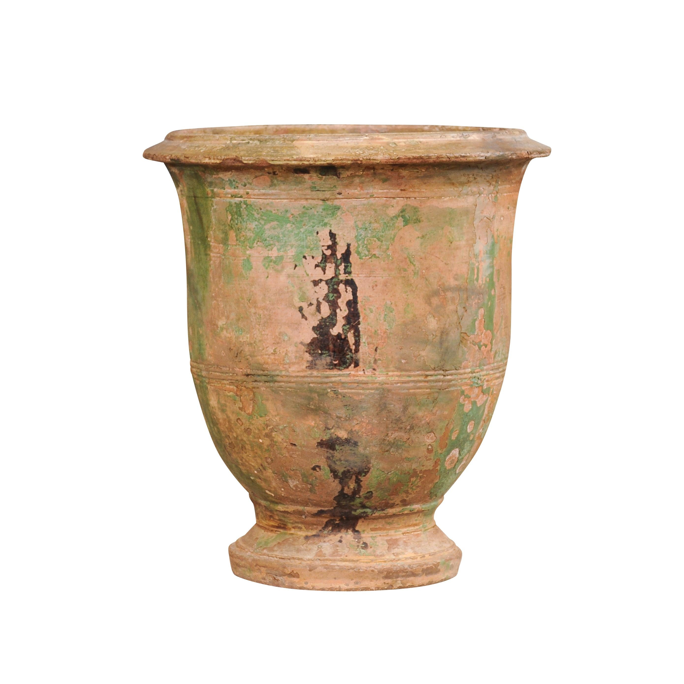 A French Provincial Anduze vase from the early 19th century with traces of green and brown glaze and nice rustic character. Steeped in rich history and displaying a rustic allure, this French Provincial Anduze vase from the early 19th century is an