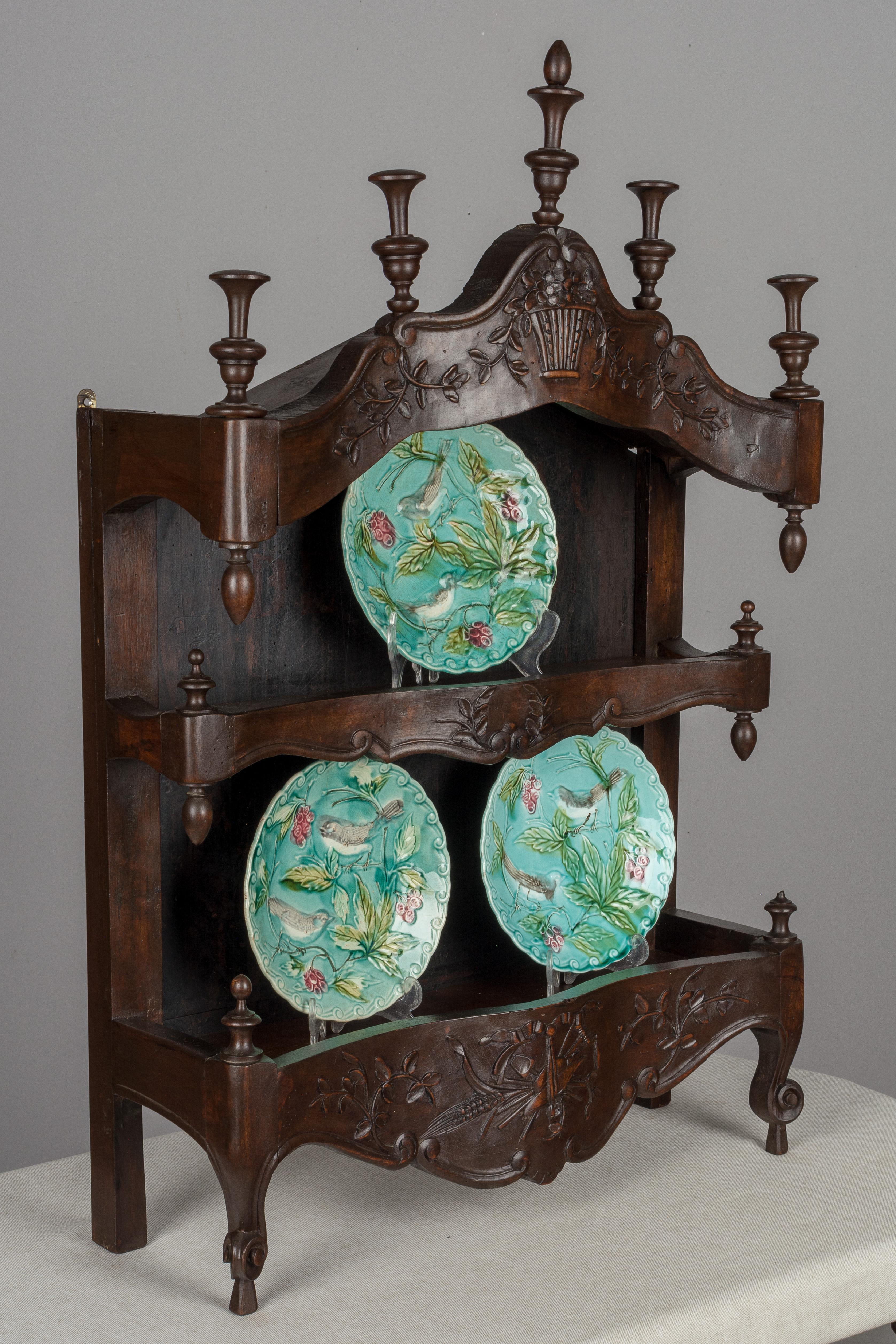 An early 19th century Louis XV style French estagnier from Provence. This lovely shelf was used to display pewter or ceramics. Made of solid walnut with serpentine front and snail toes. Beautiful hand carved relief decoration with floral and harvest