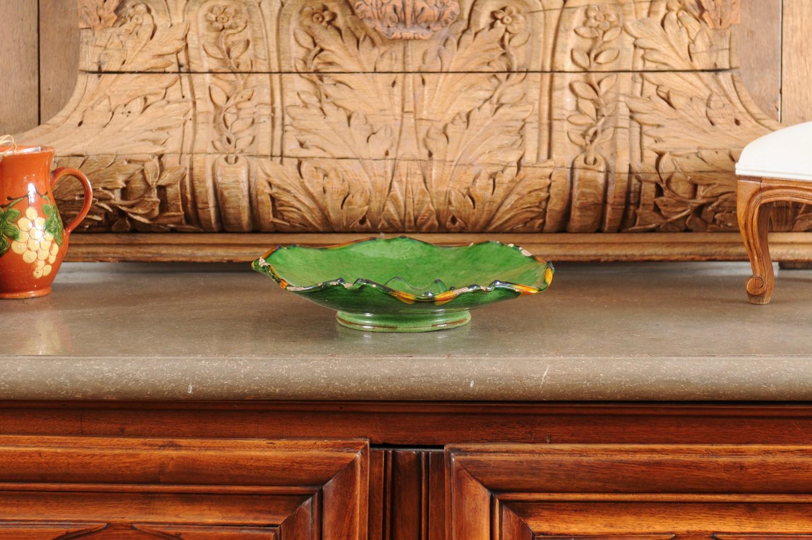 A French Provincial green glazed pottery Hors d'Œuvres dish from the mid 19th century, with scalloped edges and orange accents. Created in Provence during the reign of Emperor Napoléon III, this hors d'œuvres (appetizers) platter charms us with its