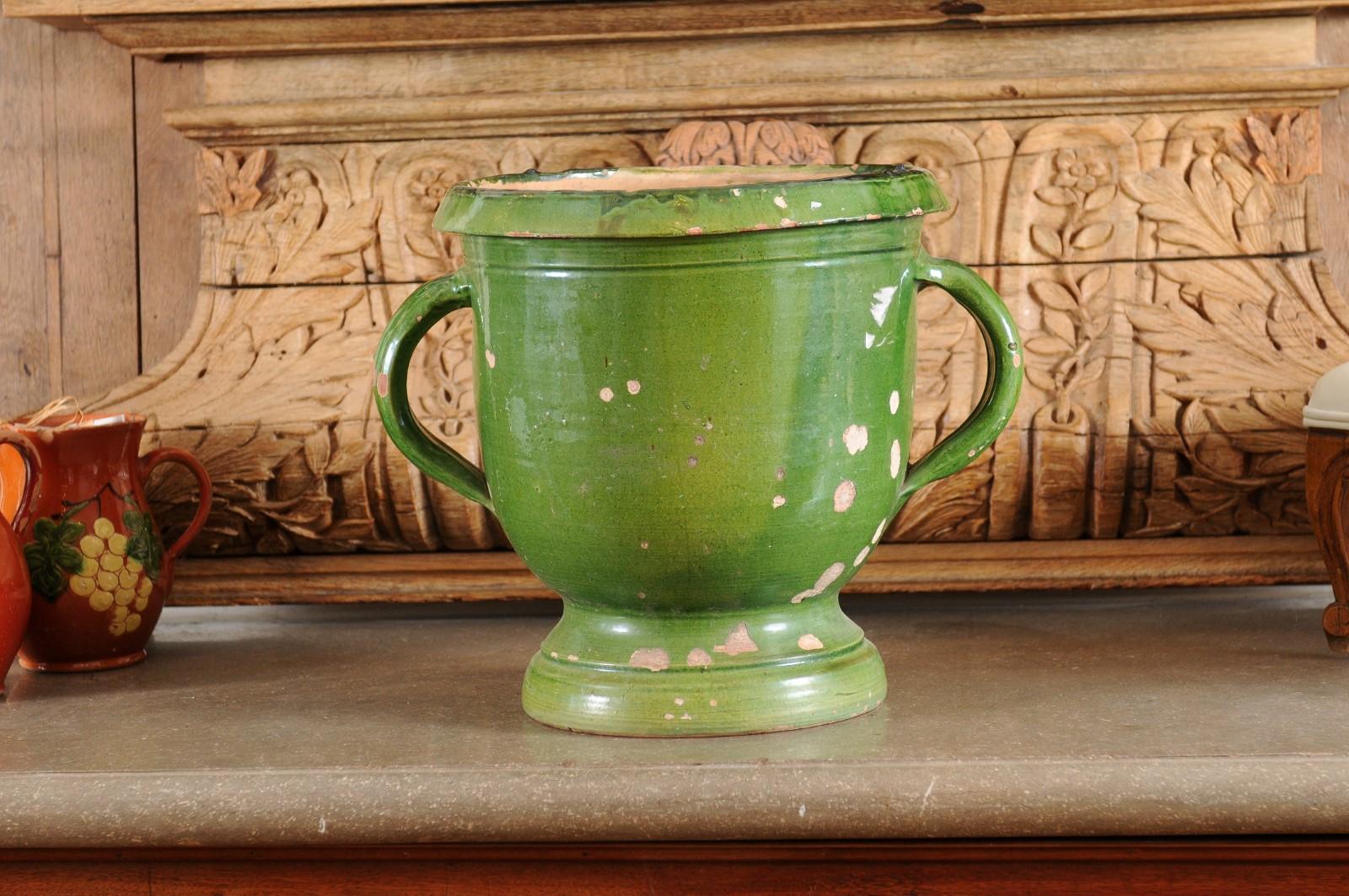 A French Provincial green glazed pottery jardinière from the mid-19th century, with lateral handles and aged patina. Created in France during the reign of emperor Napoleon III, this rustic jardinière planter features a green glazed body presenting a