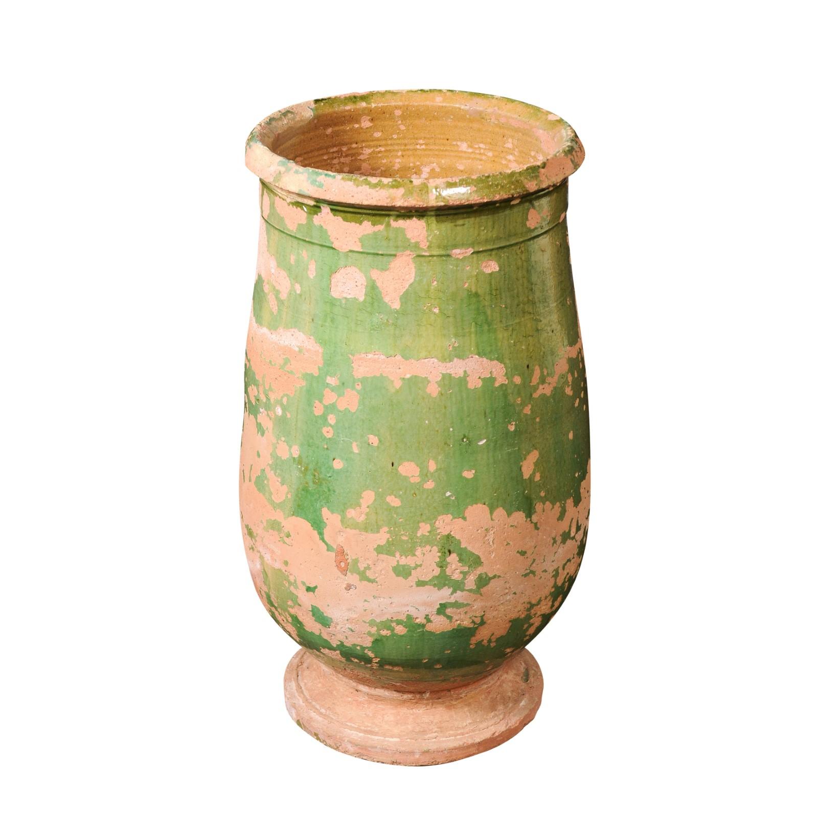 A French Provincial green glazed terracotta jar circa 1880 with oblong body, nicely weathered appearance and small base. Add a touch of rustic charm to your space with this exquisite French Provincial green glazed terracotta jar from the late 19th