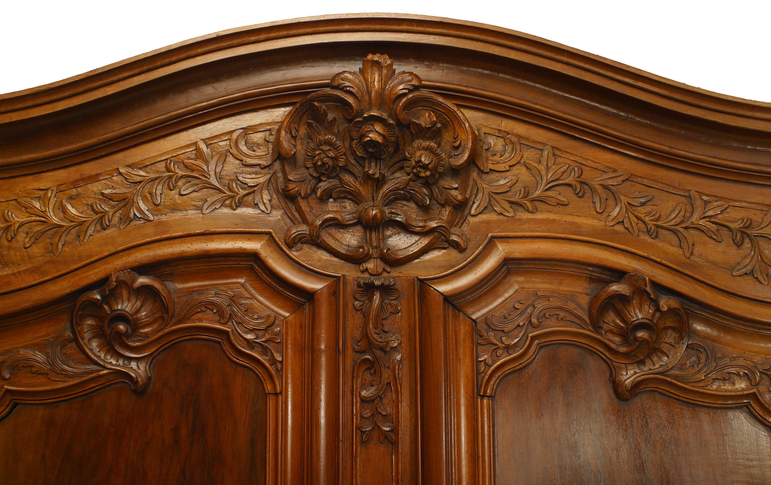 French Provincial 18th century walnut two door large scale armoire with foliate carved detail on doors and cornice with original hardware supported on a flat base.