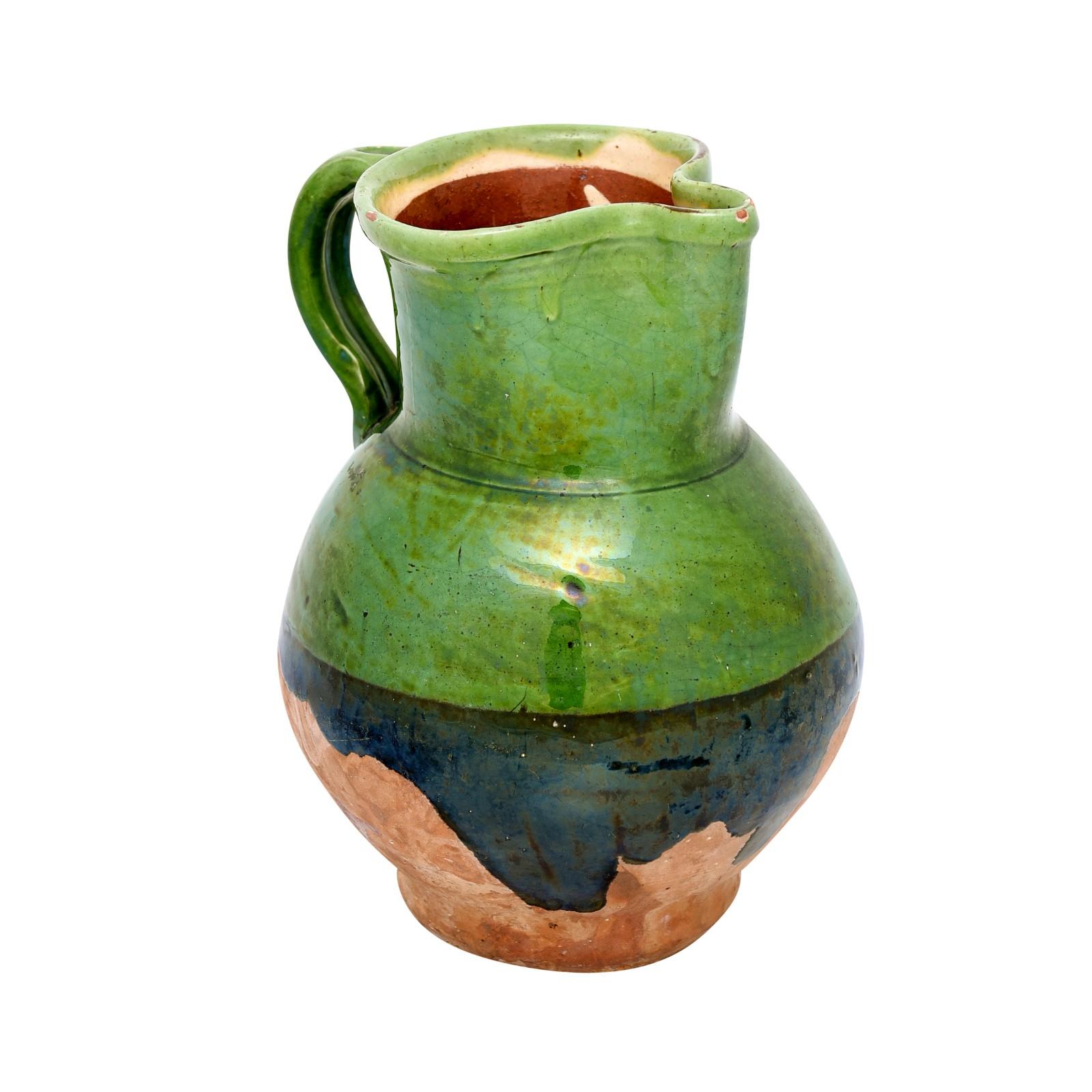A French Provincial country pottery pitcher from the 19th century, with two toned green glaze, front spout, back handle and unglazed bottom. Created in Southern France during the 19th century, this pottery pitcher features a circular shaped top with