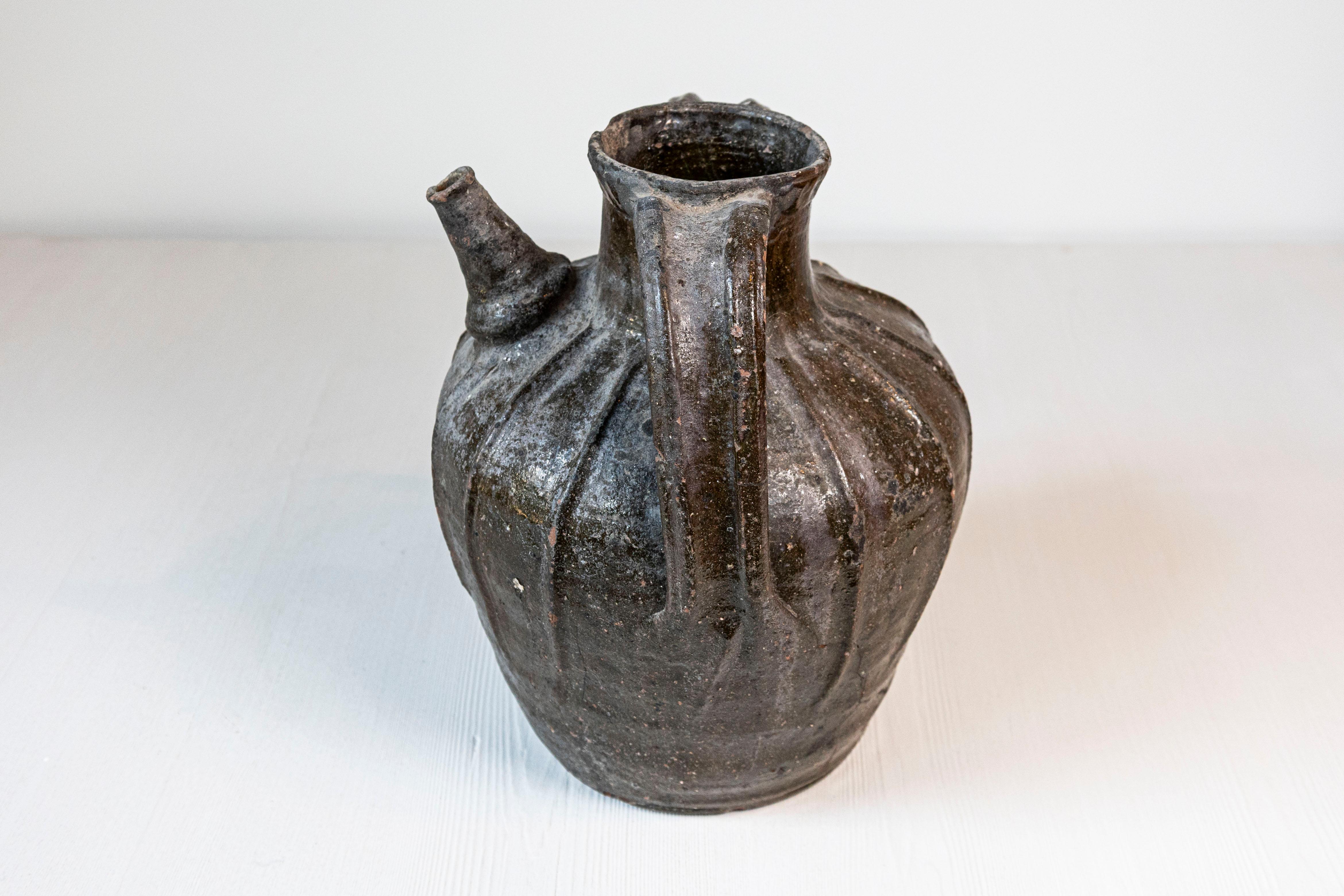 Brocca in ceramica smaltata del XIX secolo, con beccuccio singolo, due manici e grande carattere rustico. Creata nel sud della Francia durante il XIX secolo, questa brocca in ceramica attira la nostra attenzione per la sua interessante silhouette e