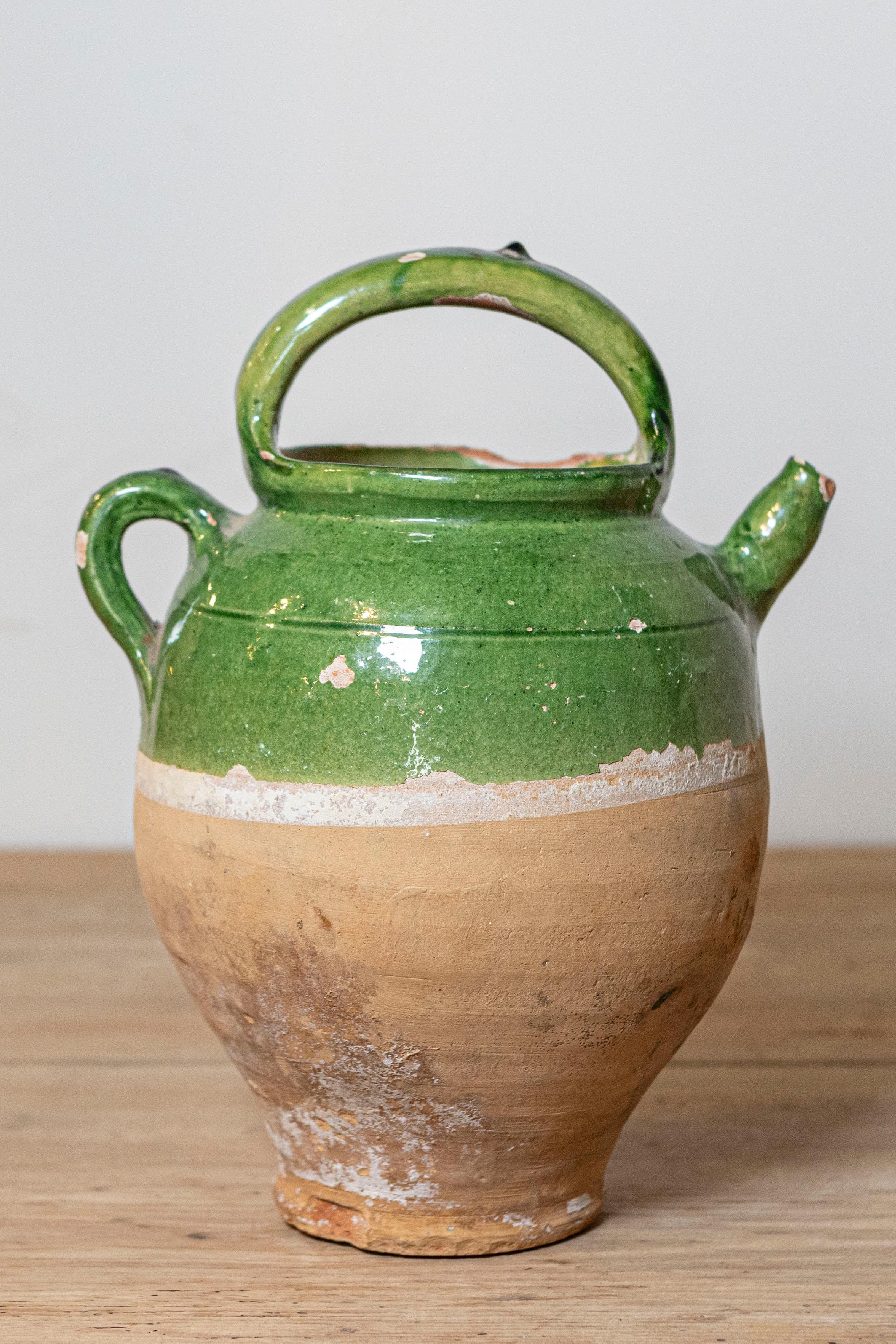 Jarra de cerámica vidriada verde de estilo provincial francés del siglo XIX, con dos asas, pico delantero y pátina desgastada. Creada en el Southern France durante el siglo XIX, esta jarra presenta una parte superior esmaltada en verde que equilibra