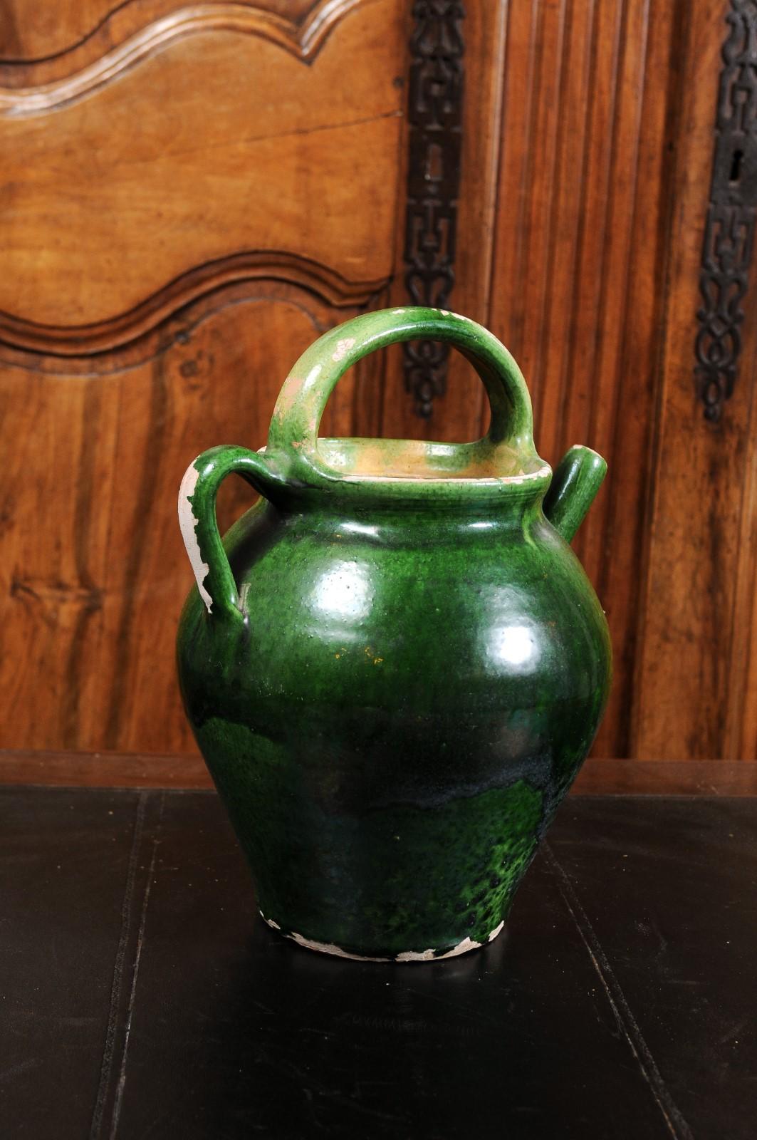 A French Provincial pottery olive oil lidded jug from the 19th century, with green glaze, two handles and distressed patina. Created in Southern France during the 19th century, this olive oil jug features a green glazed finish perfectly
