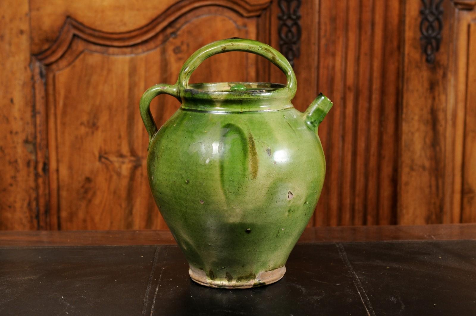 A French Provincial pottery olive oil lidded jug from the 19th century, with green glaze, two handles and distressed patina. Created in Southern France during the 19th century, this olive oil jug features a green glazed finish perfectly