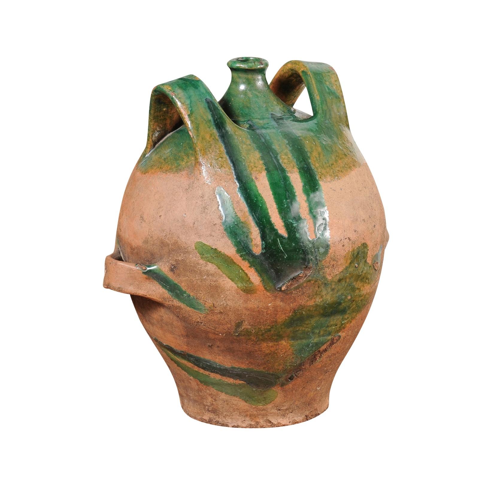 A French Provincial pottery jug from the 19th century with green glaze, dripping and lateral handles flanking the central spout. This captivating French Provincial pottery jug, crafted with meticulous care in the 19th century, is a splendid