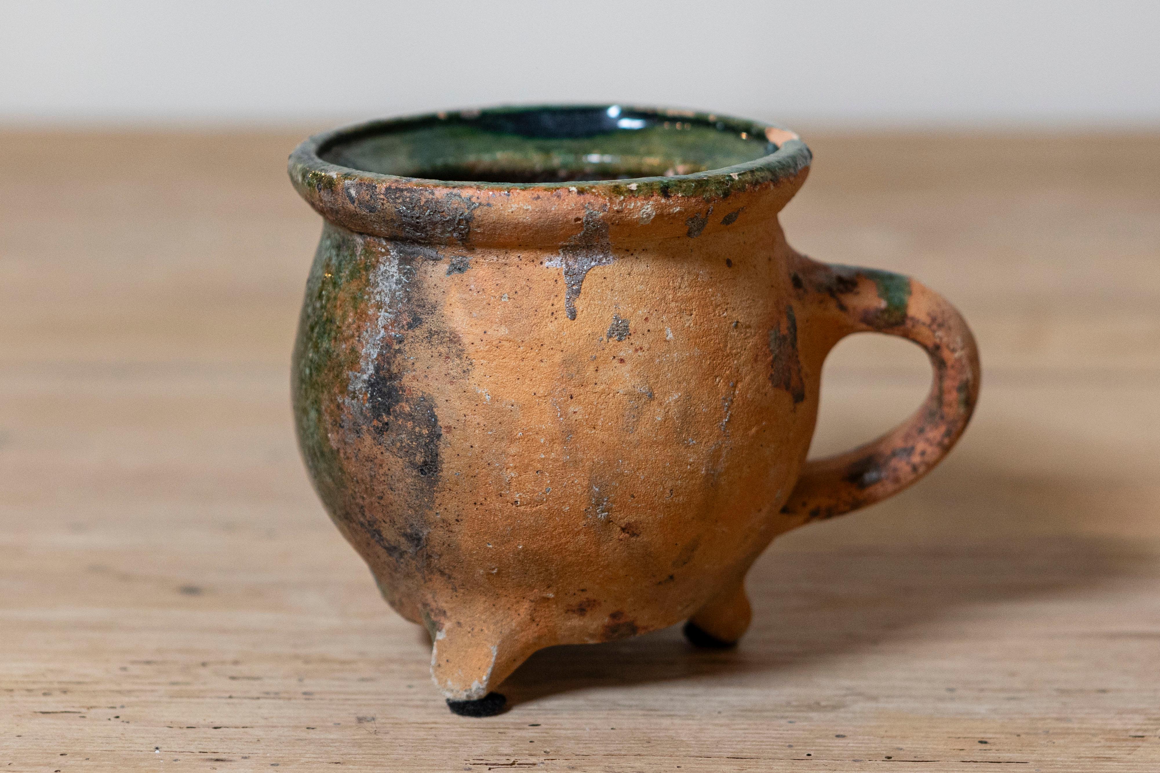 Poterie provinciale française du 19e siècle à glaçure verte, poignée moulée, base tripode et patine d'usage. Fabriquée avec précision et art, cette poterie provinciale française présente une charmante glaçure verte qui ajoute une touche d'élégance