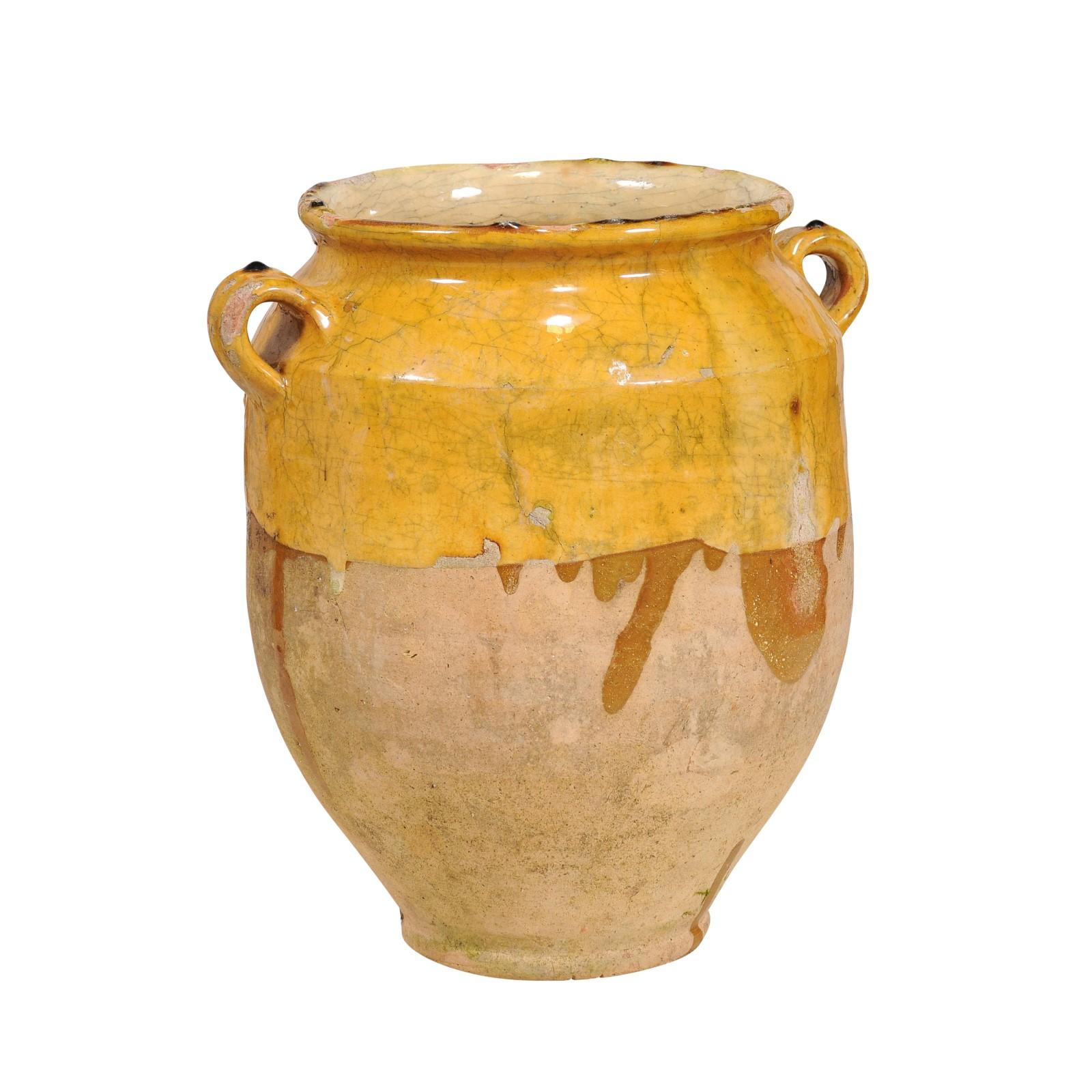 A French Provincial pot à confit pottery from the 19th century with yellow glaze, two lateral handles and rustic patina. Embrace the rustic charm and timeless tradition of this French Provincial pot à confit from the 19th century. Its sun-kissed