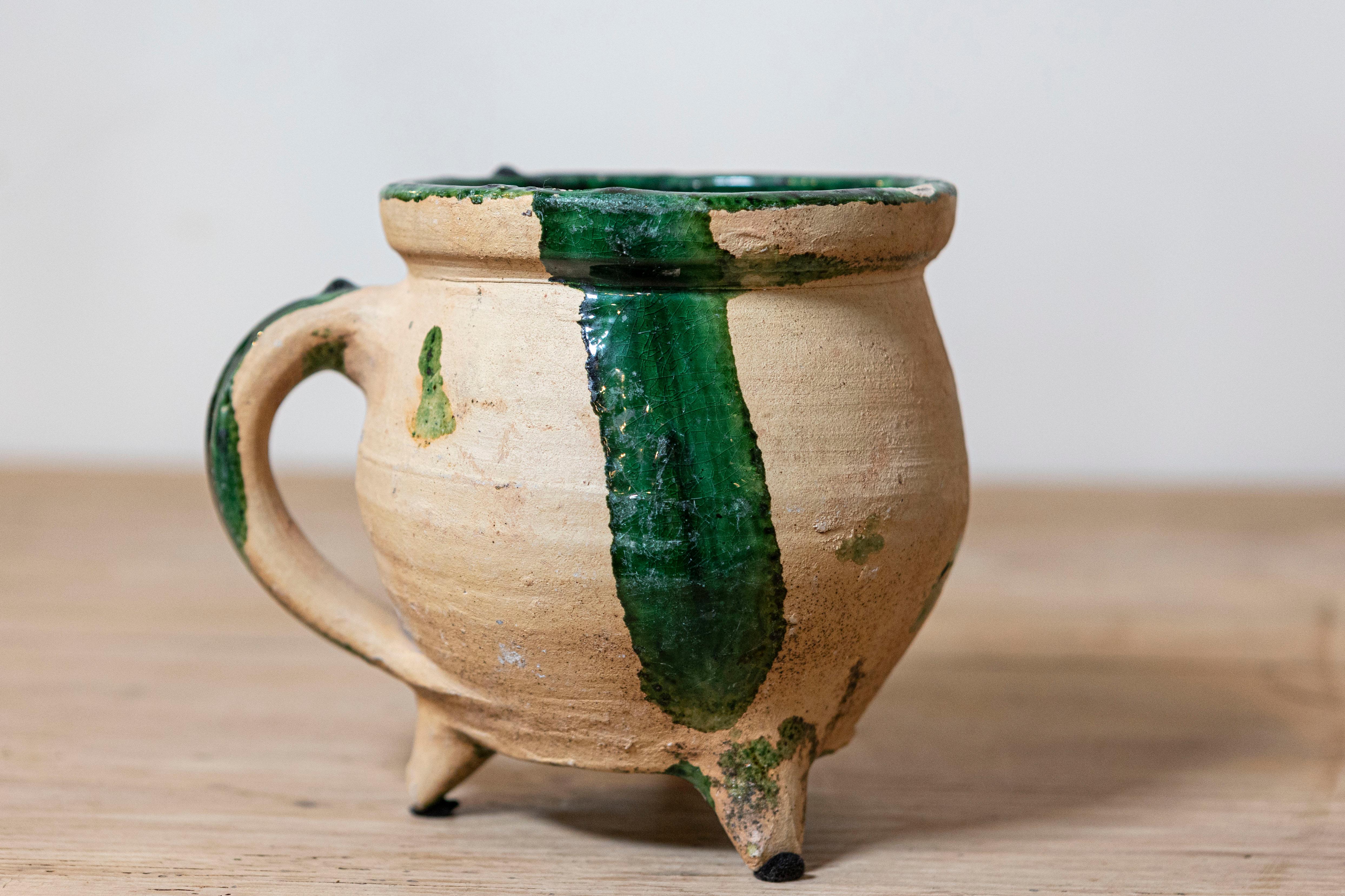 Olla de cocina de cerámica esferoidal provincial francesa del siglo XIX con detalles vidriados en verde, asa moldeada y base trípode. Creada en el Southern France durante el siglo XIX, esta olla de cerámica presenta una boca circular adornada con un