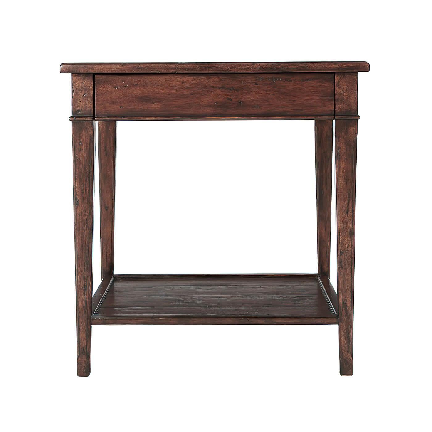 A French Provincial rustic antiqued wood bedside or end table, with a frieze drawer and the square tapering legs joined by an under tier. 

Dimensions: 26