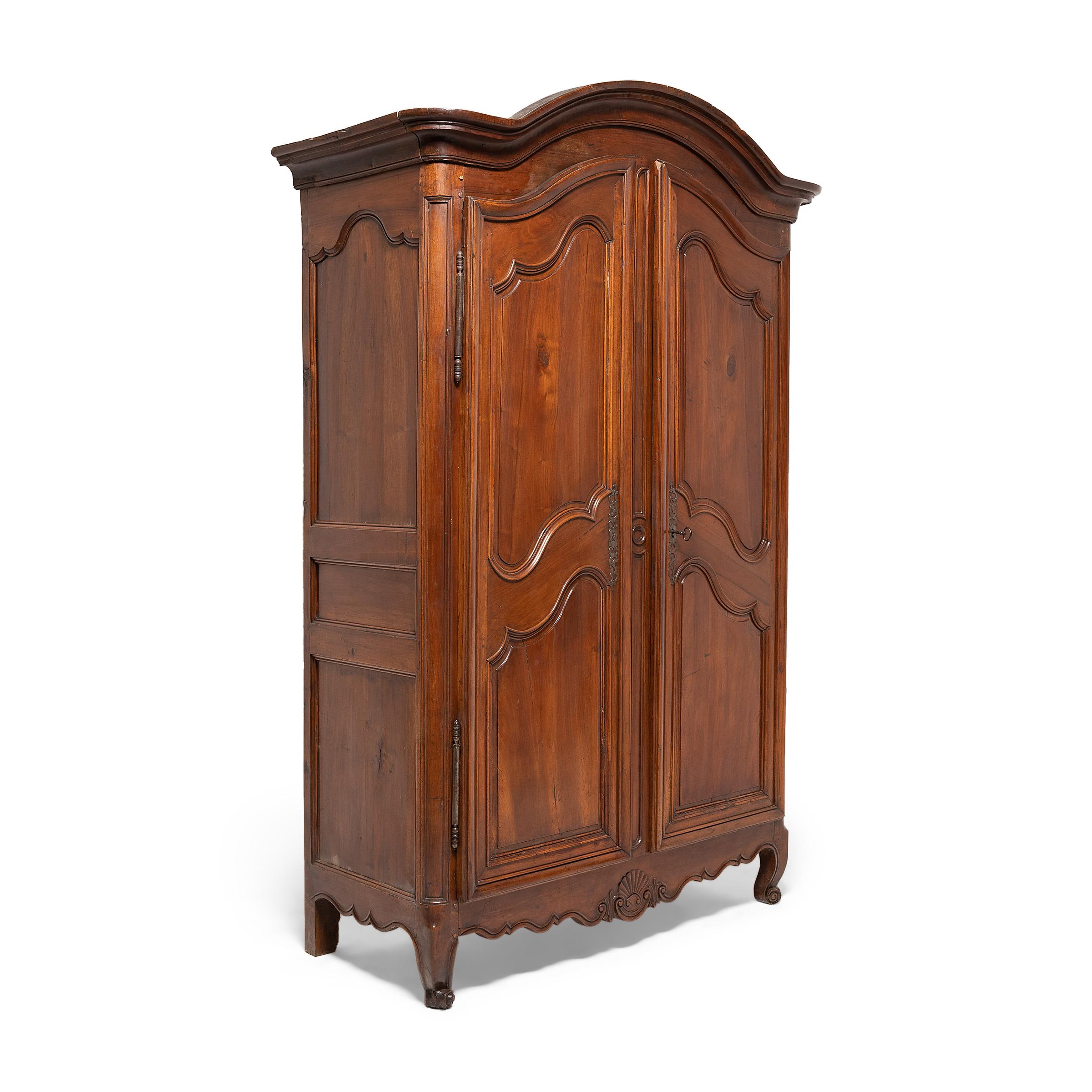 This elegant French armoire dates to the mid- to late-18th century and is a timeless example of French Provincial and Louis XV styles. The large wardrobe has a Classic form, with short cabriole legs, straight sides decorated with inset panels, and