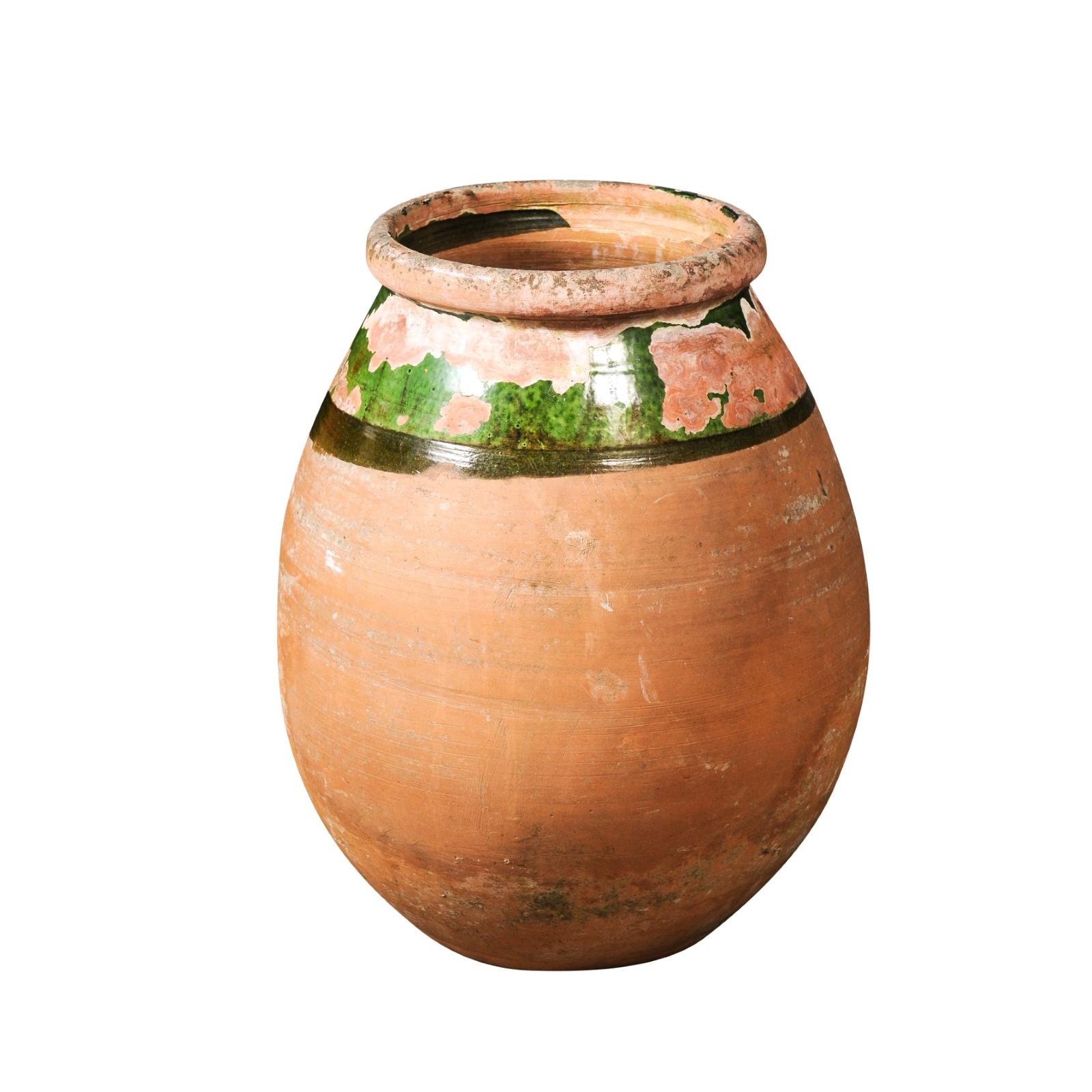 A French Provincial Biot jar from the 20th century with green glaze, generous lines and great weathered patina. Infuse your interior with the bucolic charm of the French Povençale region through this captivating French 20th century glazed Biot jar.