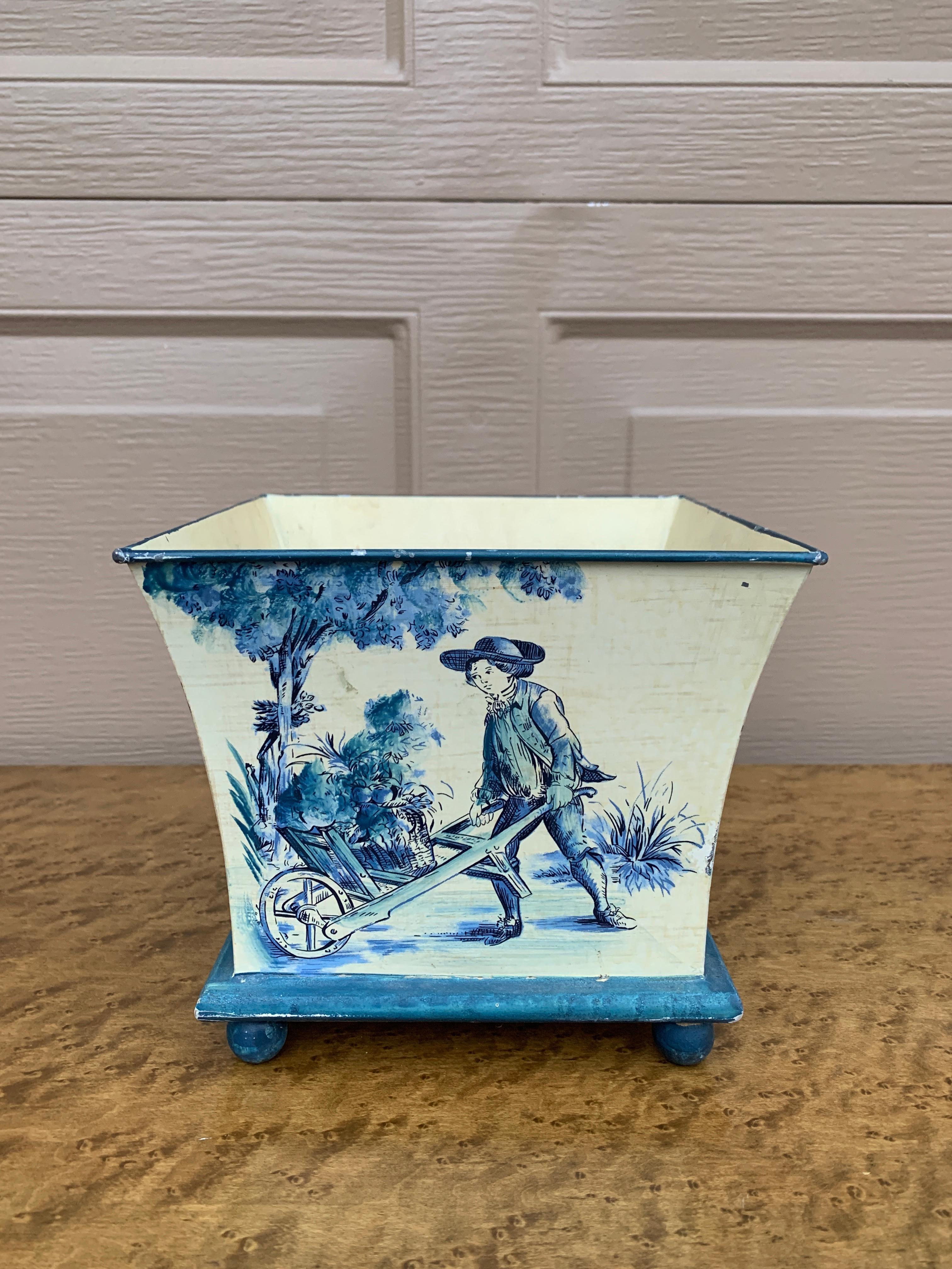 Un magnifico cachepot, una fioriera o un vaso in tole blu e crema, in stile neoclassico o provinciale francese, con scene di campagna.

Stati Uniti, fine del XX secolo

Misure: 7,25