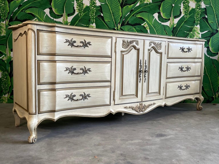 Vintage 20th century French provincial dresser features bombe style detailing, cabriole legs, and scrolled feet. Shaped top and skirt along with bronze hardware. Good condition with minor imperfections consistent with age. May exhibit scuffs, marks,