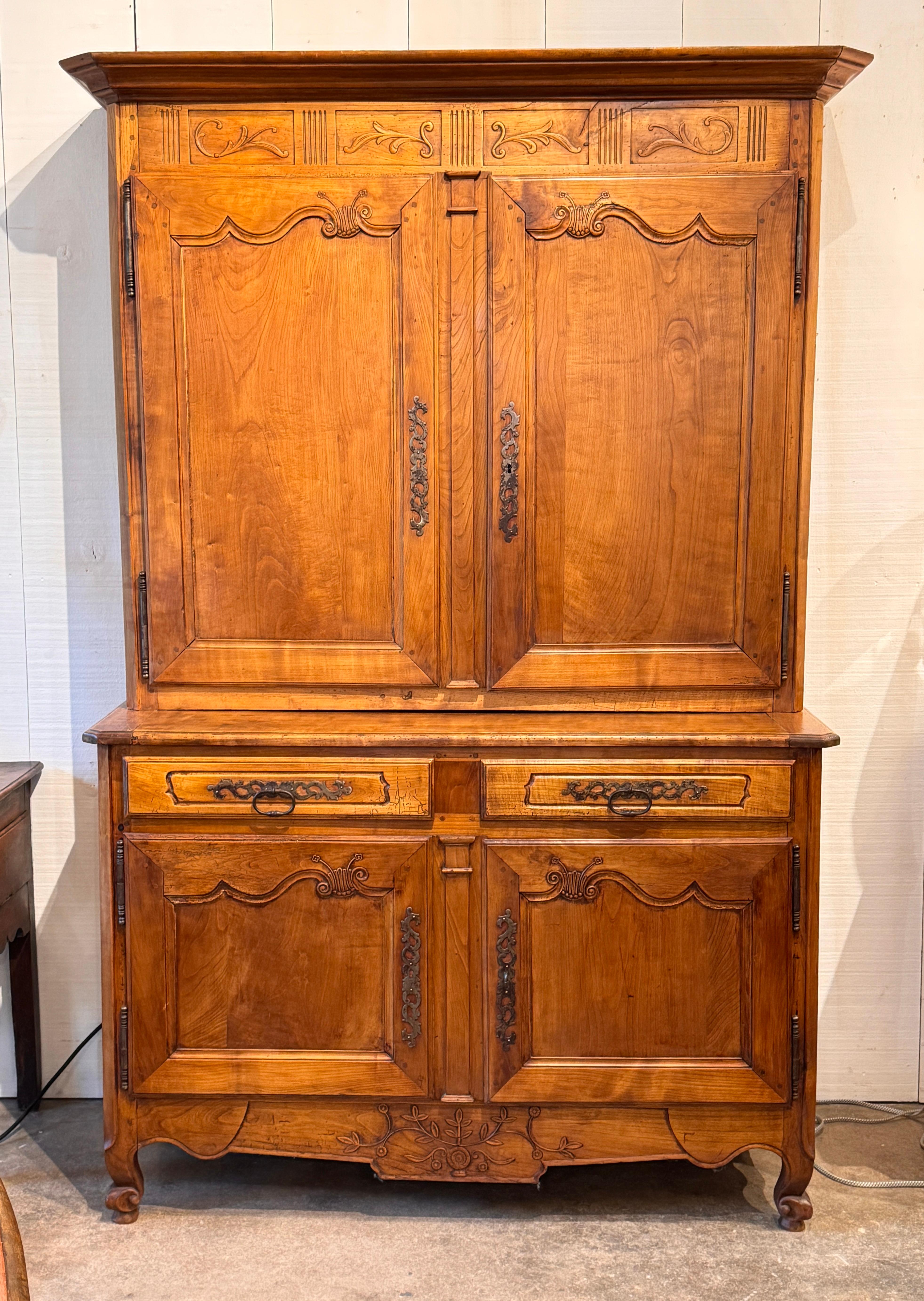 Französischer Provinzialschrank mit klassischen geschnitzten Verzierungen an Türen und Schürze, geformten Paneelen und originalen Eisenbeschlägen. Die warme Patina und das sichtbare Alter des Holzes spiegeln sowohl die Zweckmäßigkeit als auch die