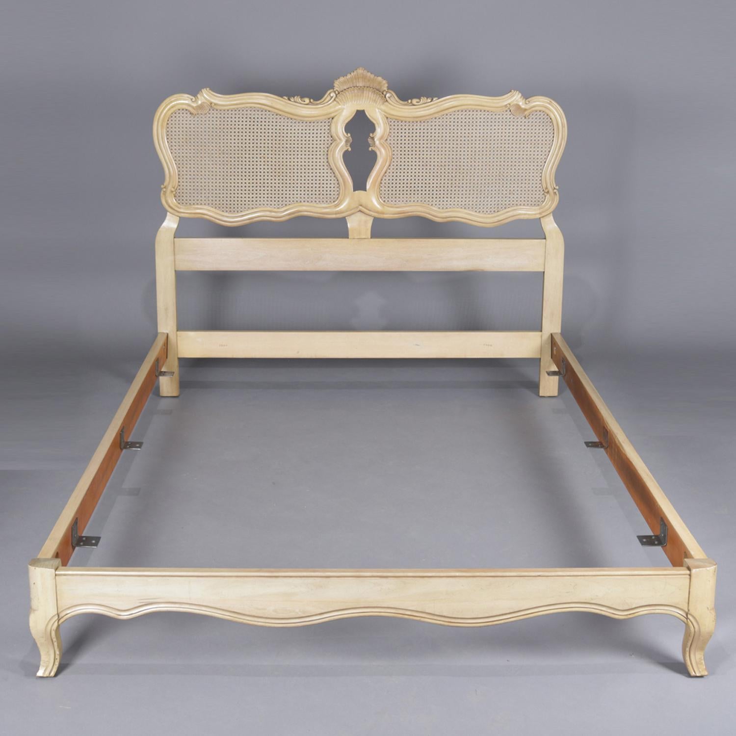 A vintage French Provincial style full/double bed frame by John Widdicomb features double caned panels framed by scrolled frames and joined by stylized carved central shell, raised on cabriole legs and with white washed painted finish, 20th