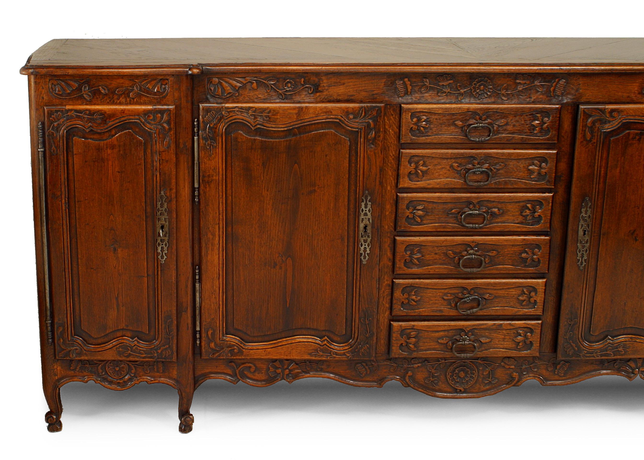 French Provincial Louis XV style 19th century oak buffet cabinet embellished with carved floral trim and designed with 2 pair of side doors and 6 drawers in the center.