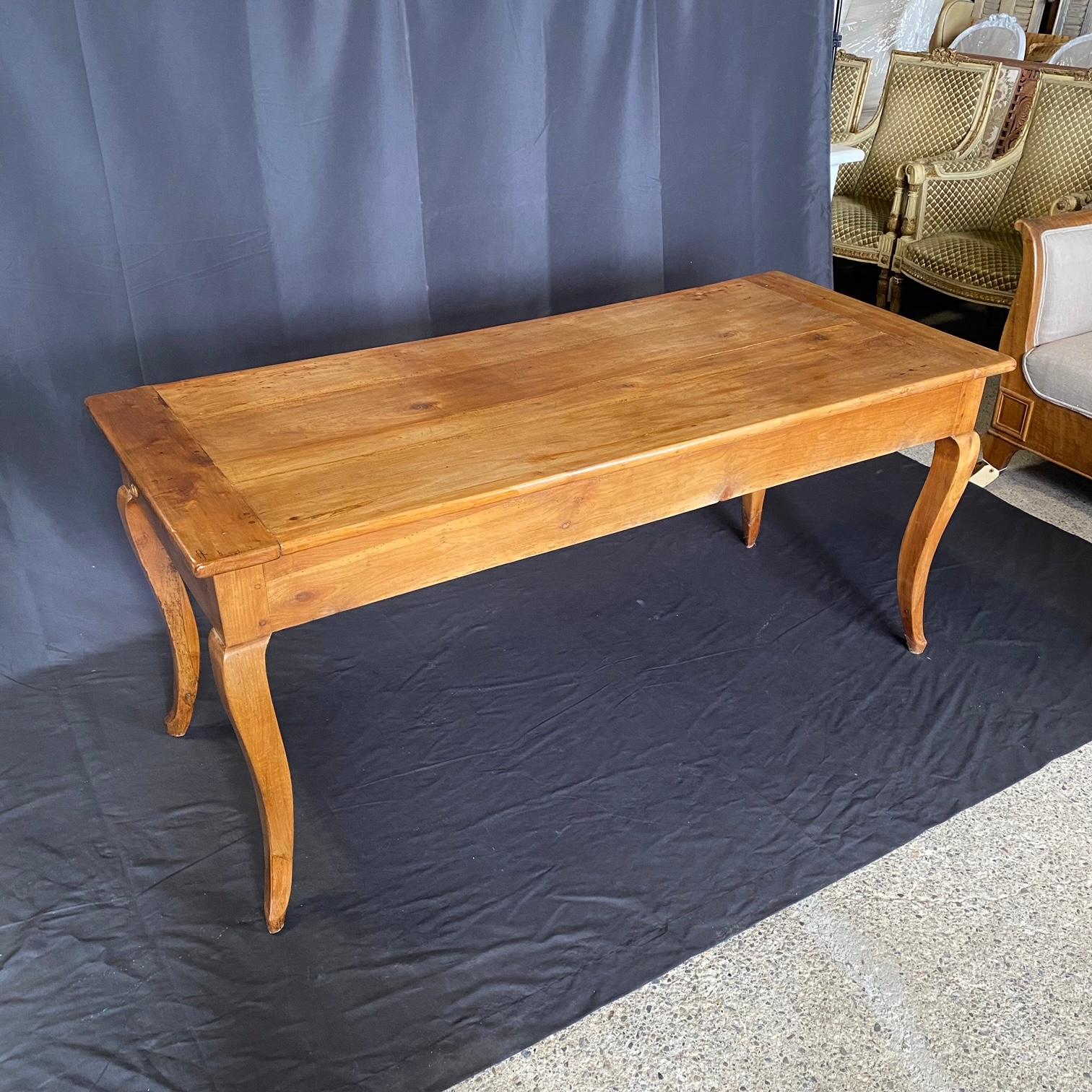 Elégante et charmante table de salle à manger en cerisier français du XIXe siècle. Cette exquise table de salle à manger française ancienne est un trésor intemporel qui offre à la fois fonctionnalité et élégance. Avec une planche à pain extractible