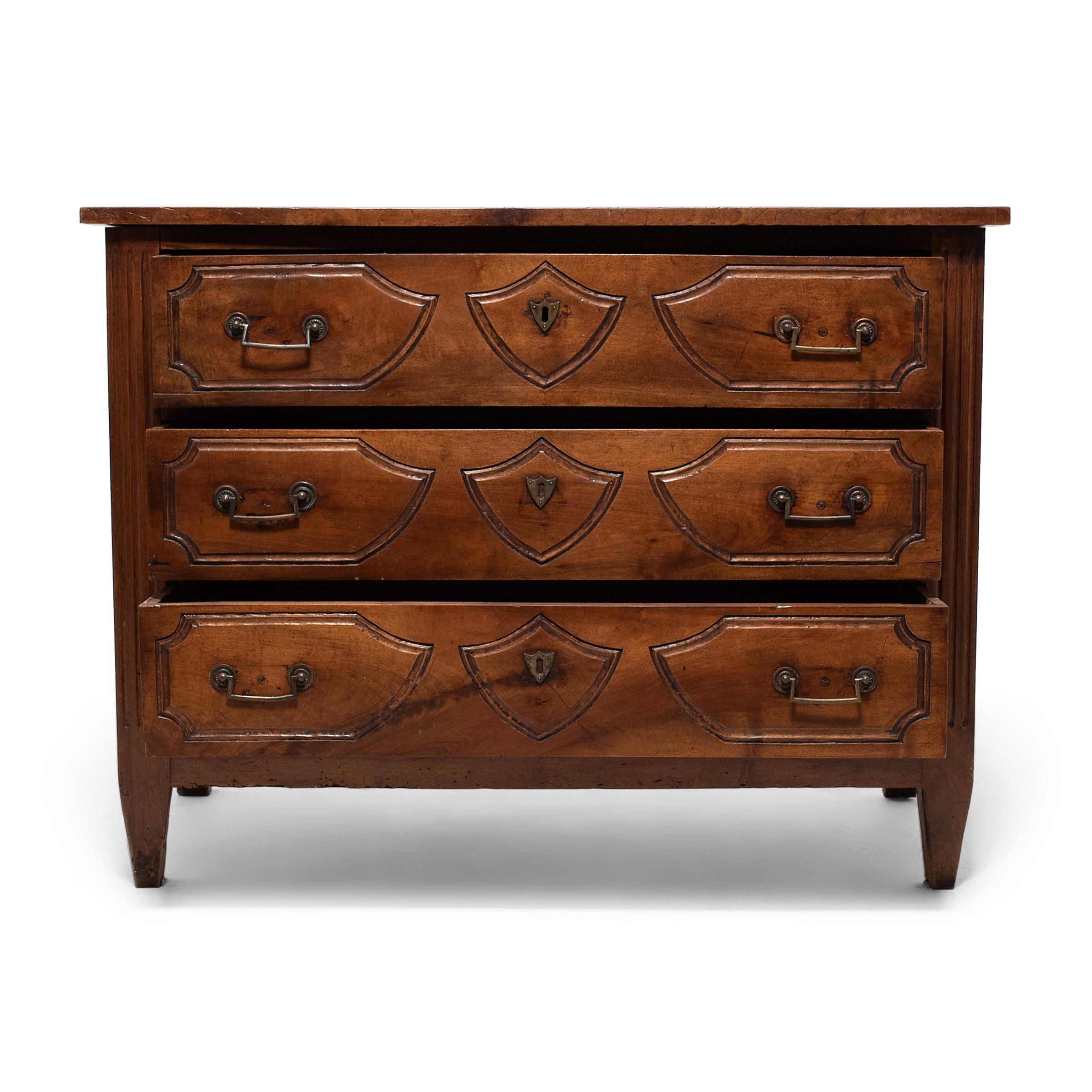 This 19th century chest of drawers is crafted of oak in the French provincial style, with simple form and minimal decoration. The cabinet displays elements of both the ornately carved Louis XV-style commodes and the clean lined cabinets of the