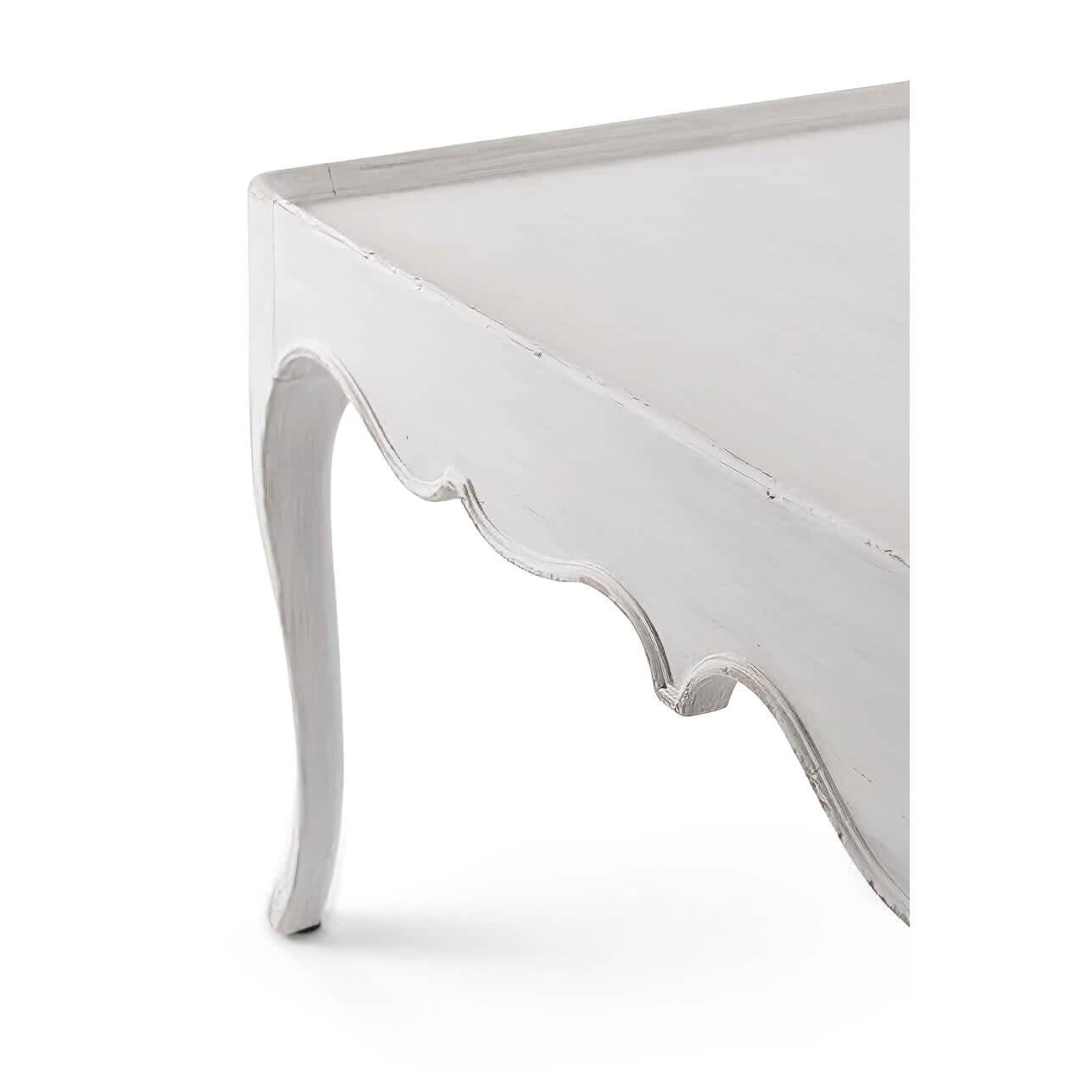 A French Provincial coffee table in a white painted finish, with a dish top, scalloped aprons and cabriole legs.

Dimensions: 52