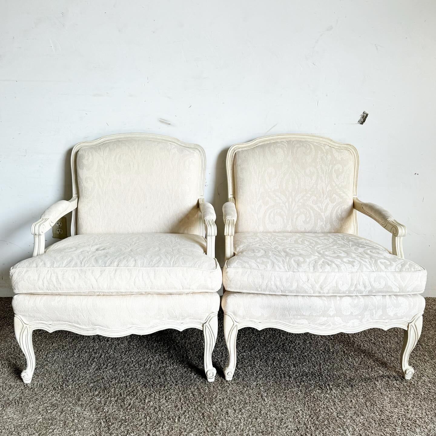 Ajoutez une touche d'élégance classique à votre espace avec ces chaises à accoudoirs de style provincial français crème/blanc cassé. Avec leurs détails complexes et leur silhouette gracieuse, ces chaises sont revêtues d'un tissu doux crème/blanc