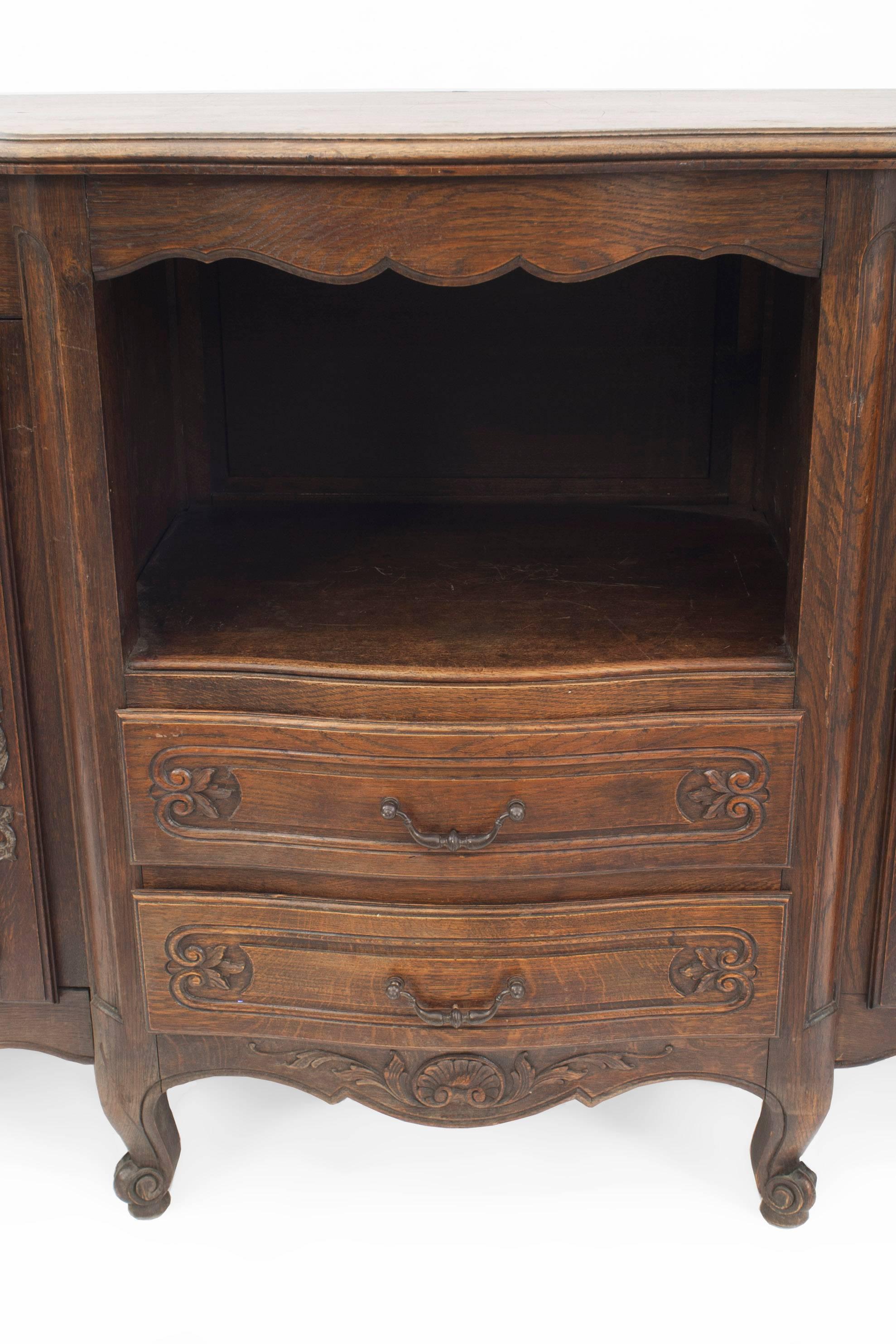 French Provincial dark stained oak sideboard / credenza with an open shelf over two drawers centering two cabinet doors with carved detail (19th century).
 