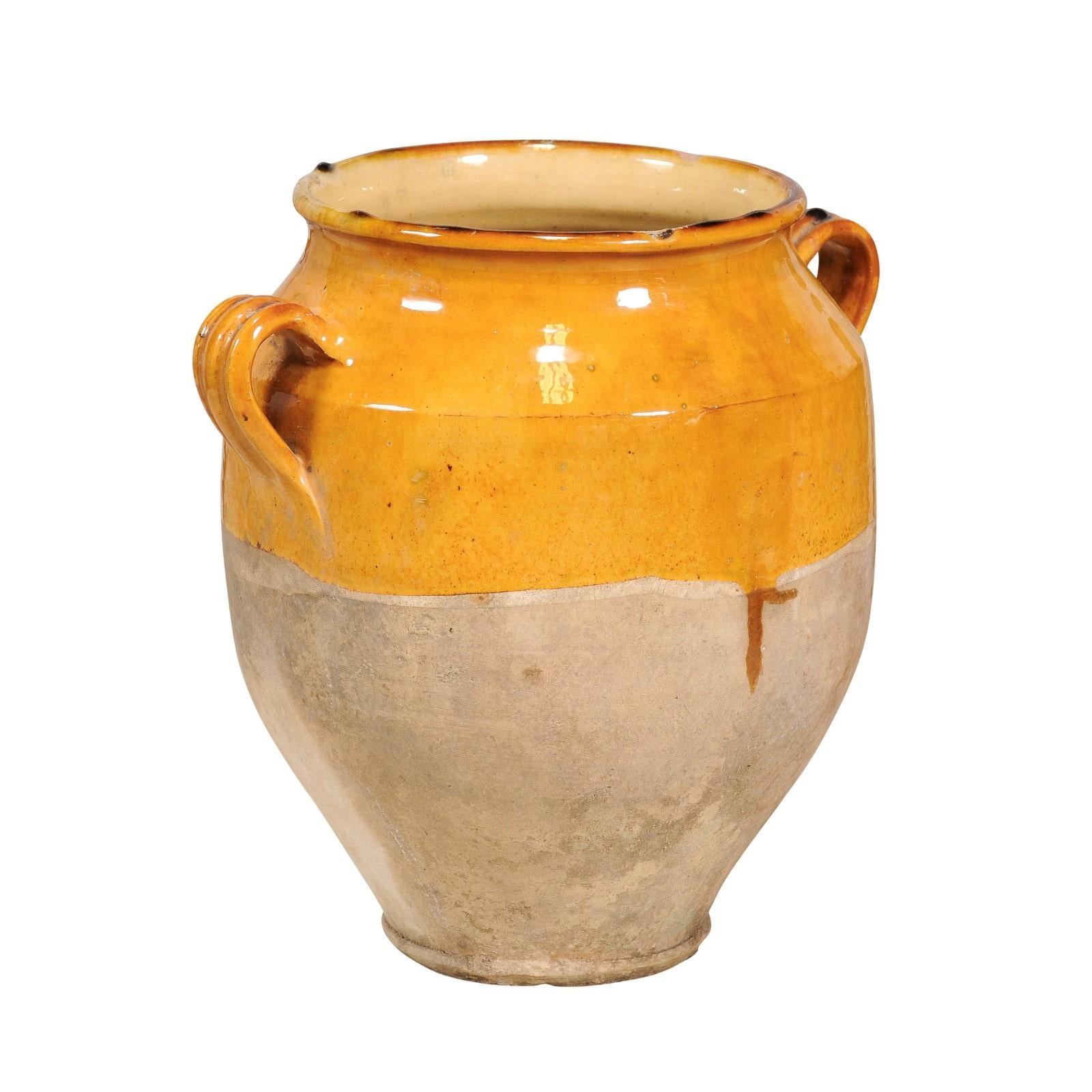 A French Provincial pot à confit pottery from the 19th century with yellow glaze, two lateral handles and rustic patina. This 19th-century French Provincial pot à confit is a charming relic of rustic culinary history, boasting a warm yellow glaze