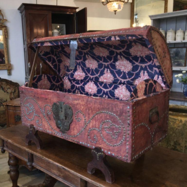 Gorgeous 18th-19th century French Provincial marriage or dowry chest of a nice, smaller size, leather-covered with original hardware, beautiful tack decoration, and a stand, lined with vibrant period toile de jouy in excellent condition. With early