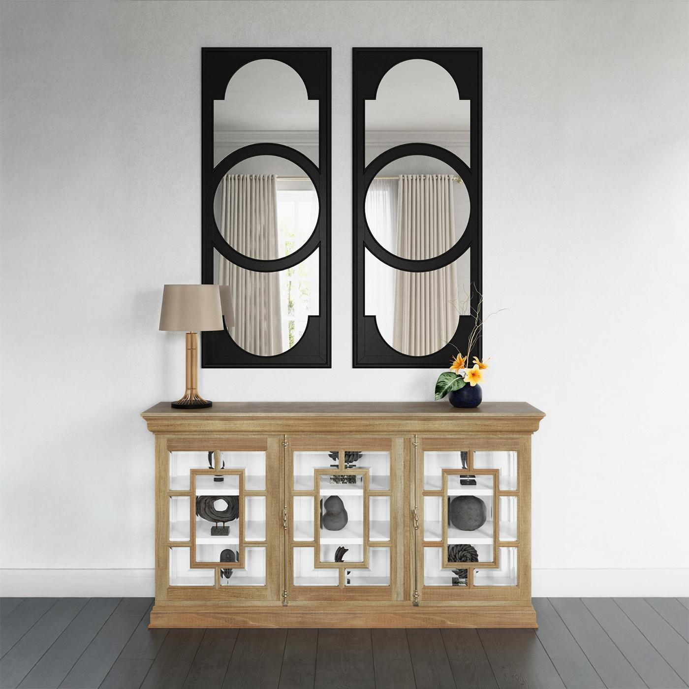 Incorniciate da una finitura in legno di frutta, le sue ante con pannelli di vetro presentano un traforo geometrico in un motivo stilizzato che evoca i classici motivi francesi. Dietro ogni pannello, un vero e proprio interno dipinto di bianco offre