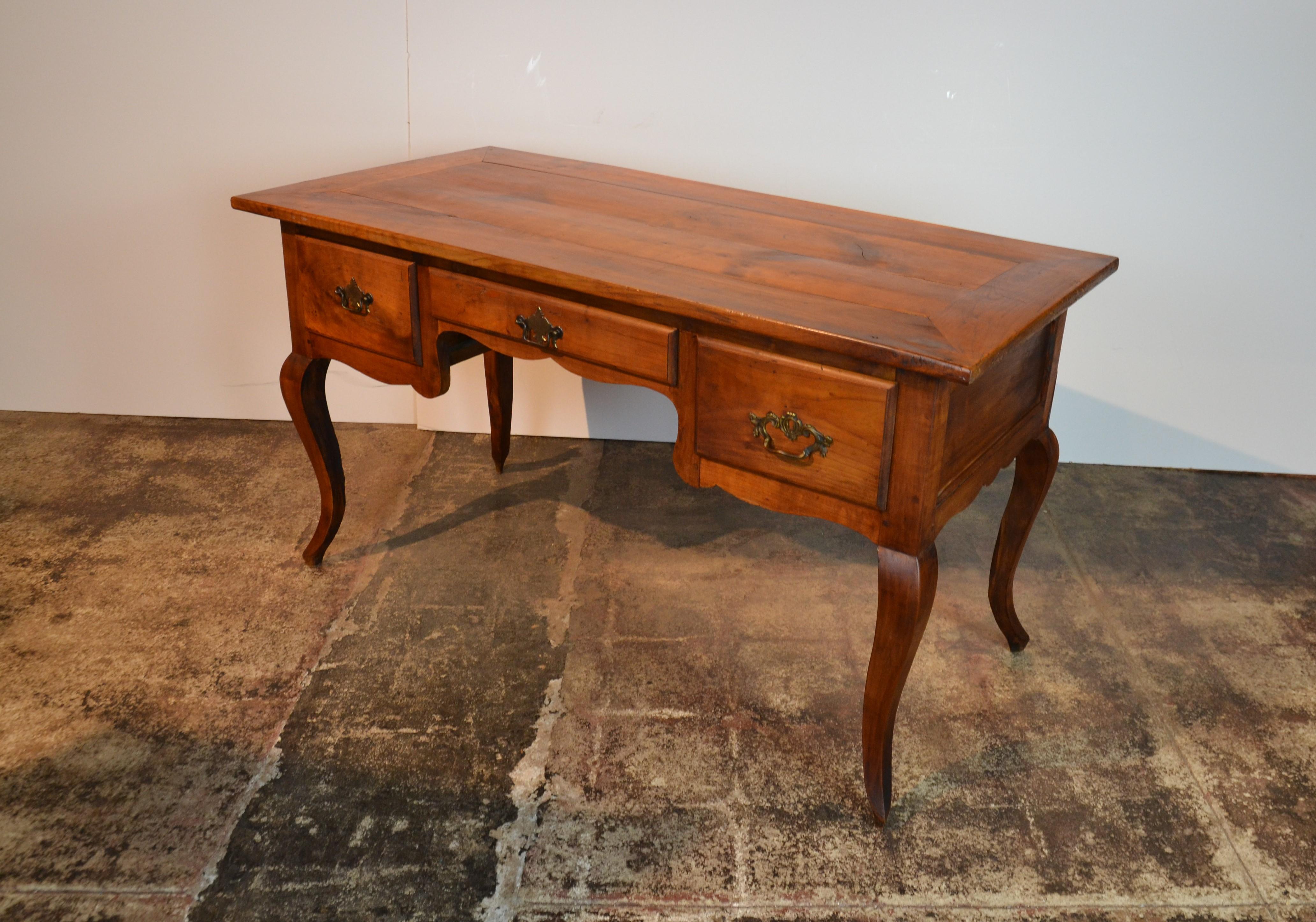 A French Provincial fruitwood desk in the Louis XV style. Solid fruitwood with 3 drawers to the front. Inset panels to the sides.